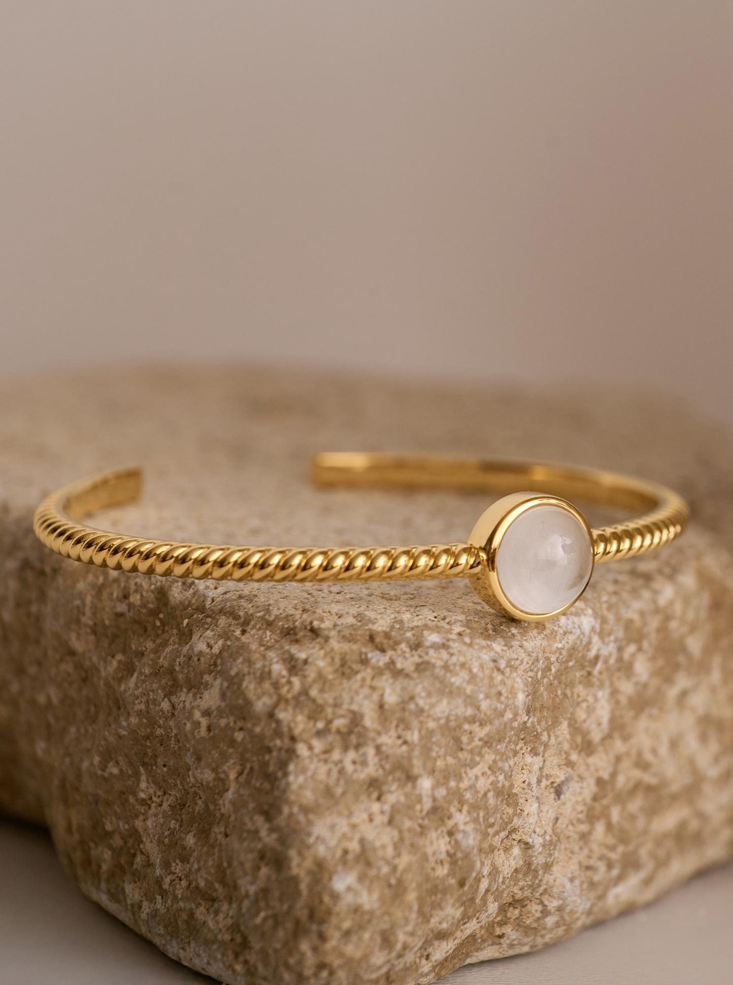 Gold Tarini Cuff with moonstone talisman on textured stone background