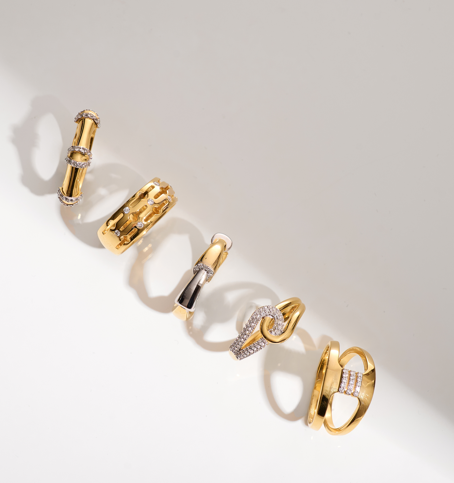 Close-up of Ansh Ring collection featuring gold and white topaz geometric designs on a white background