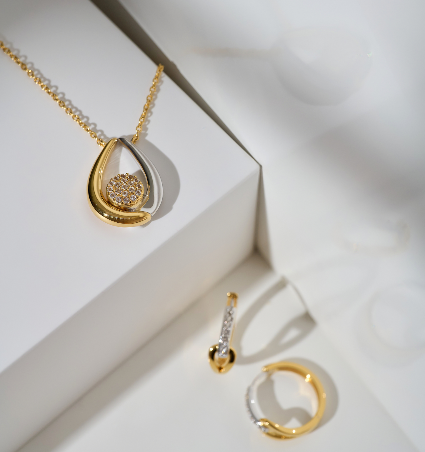 Antara Necklace with twin gold and silver arcs surrounding a cluster of 19 white topaz stones.