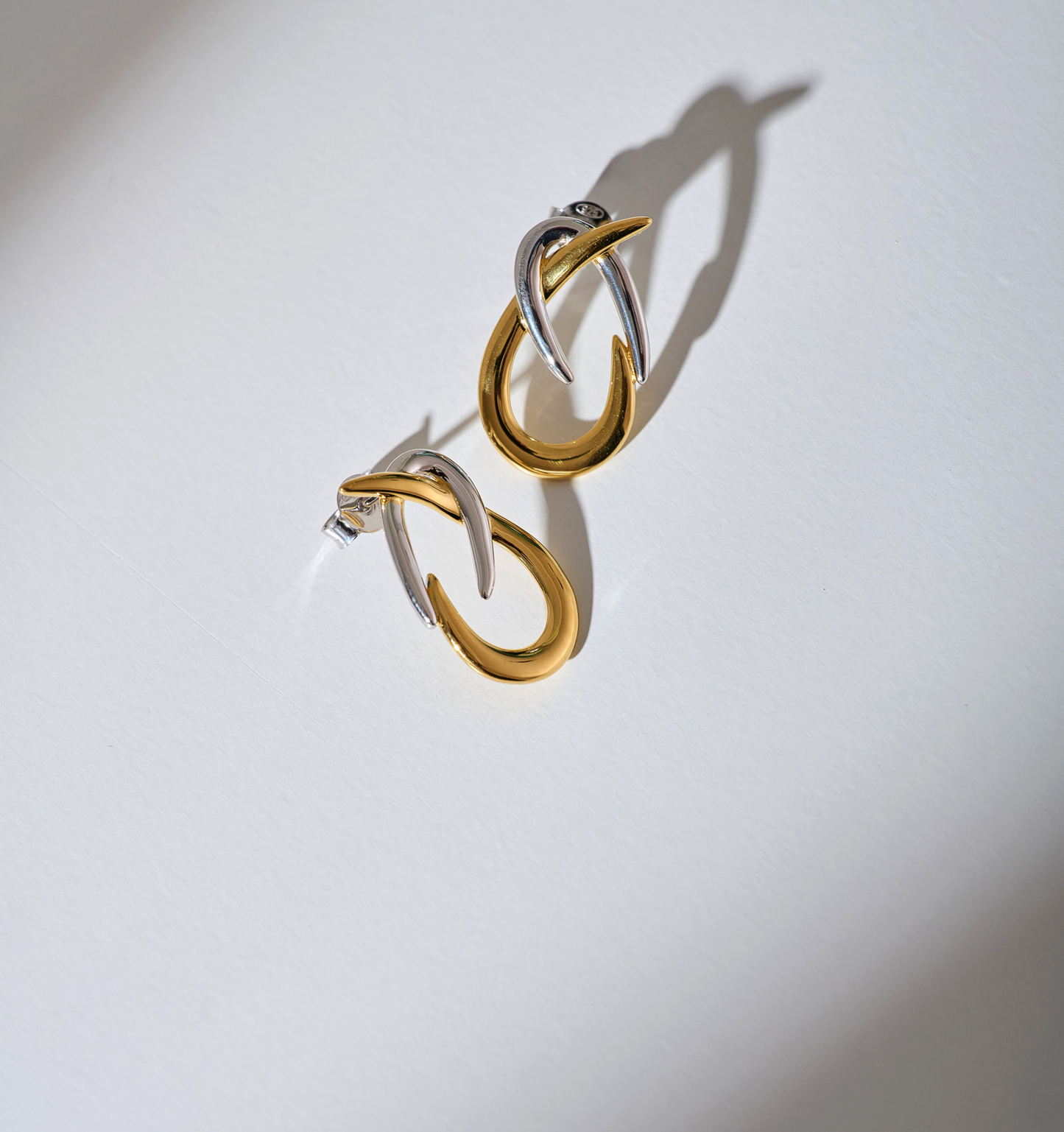 Syra Earrings gold and silver interlocking arcs design on white background