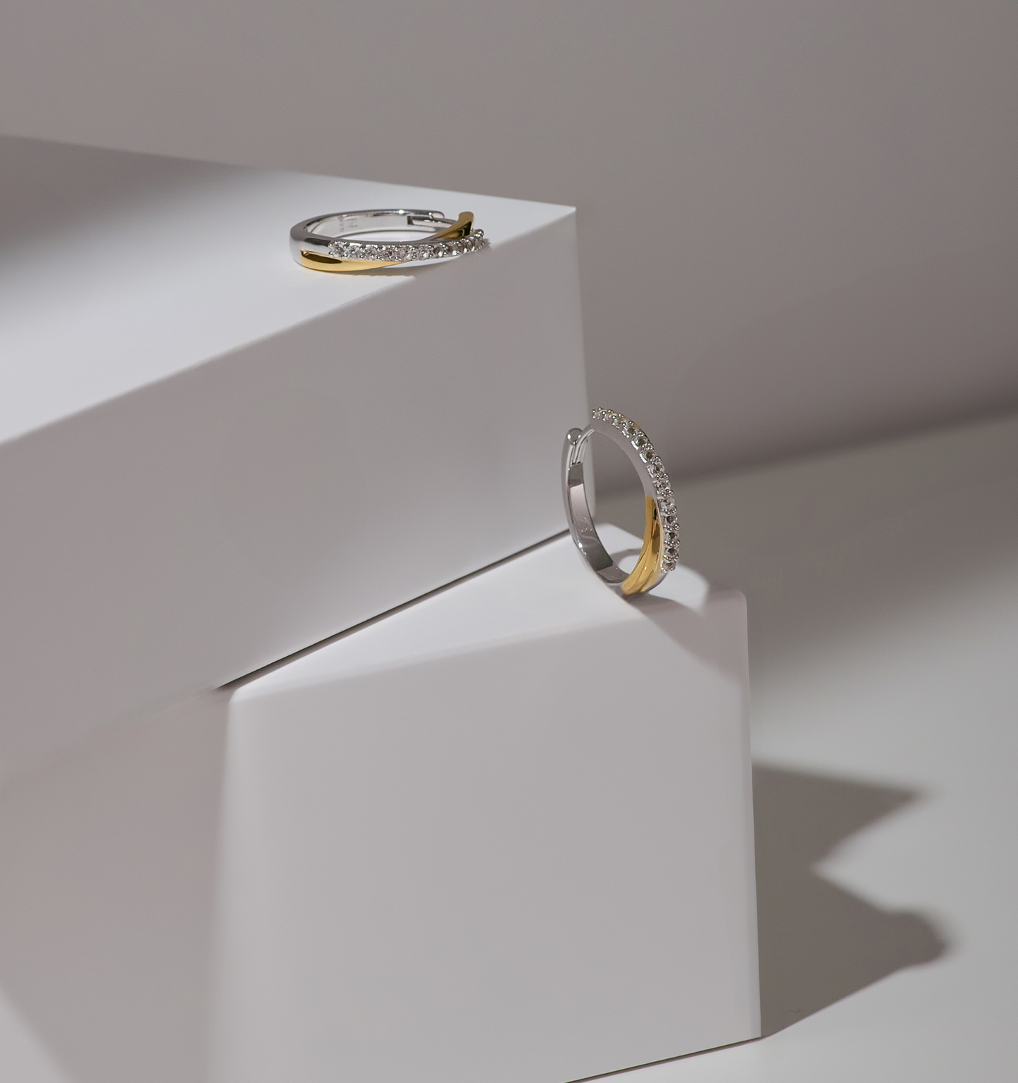 Mishri Hoops silver and gold earrings with white topaz detailing on white geometric display