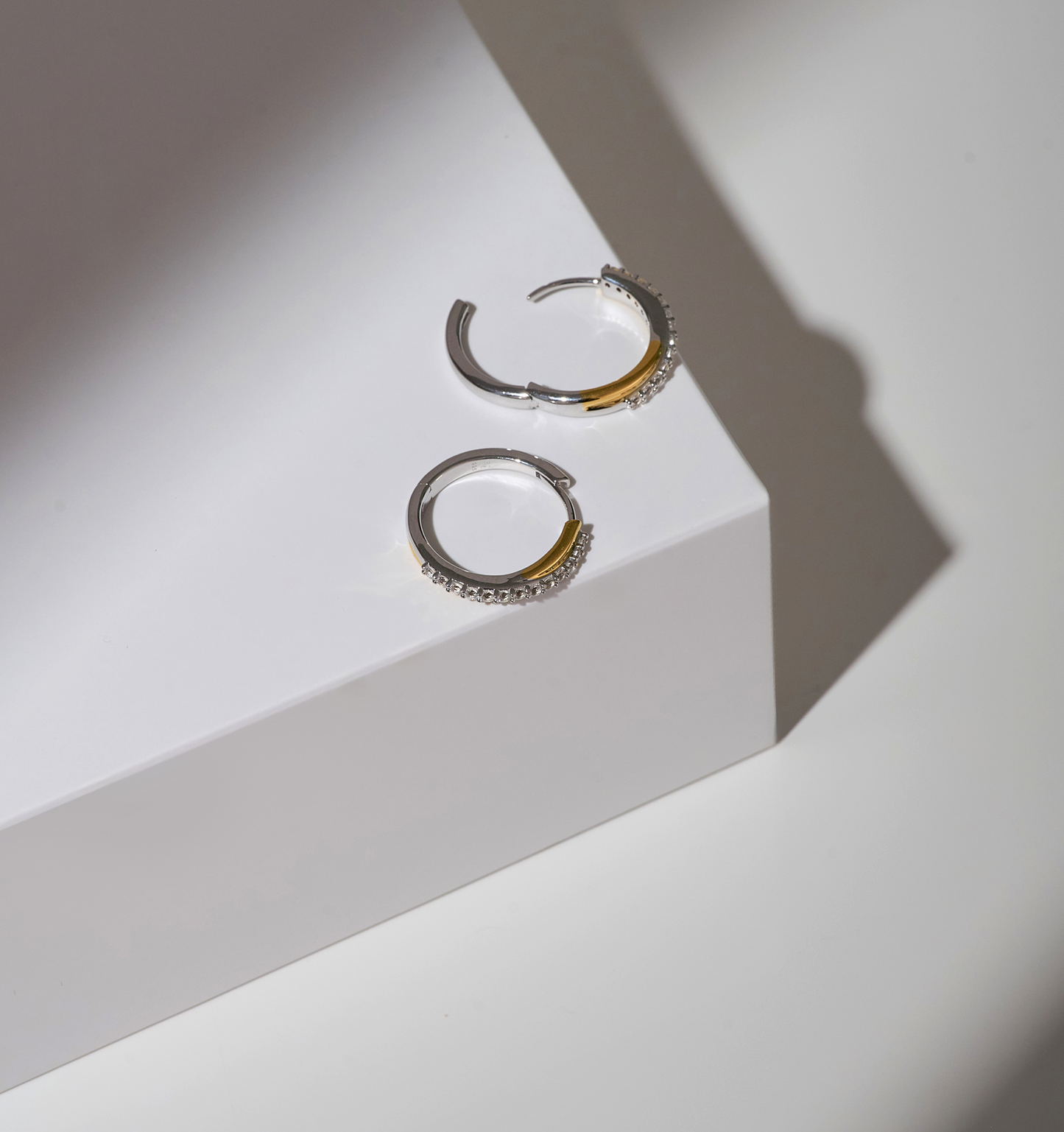 Mishri Hoops silver and gold earrings with white topaz on white surface
