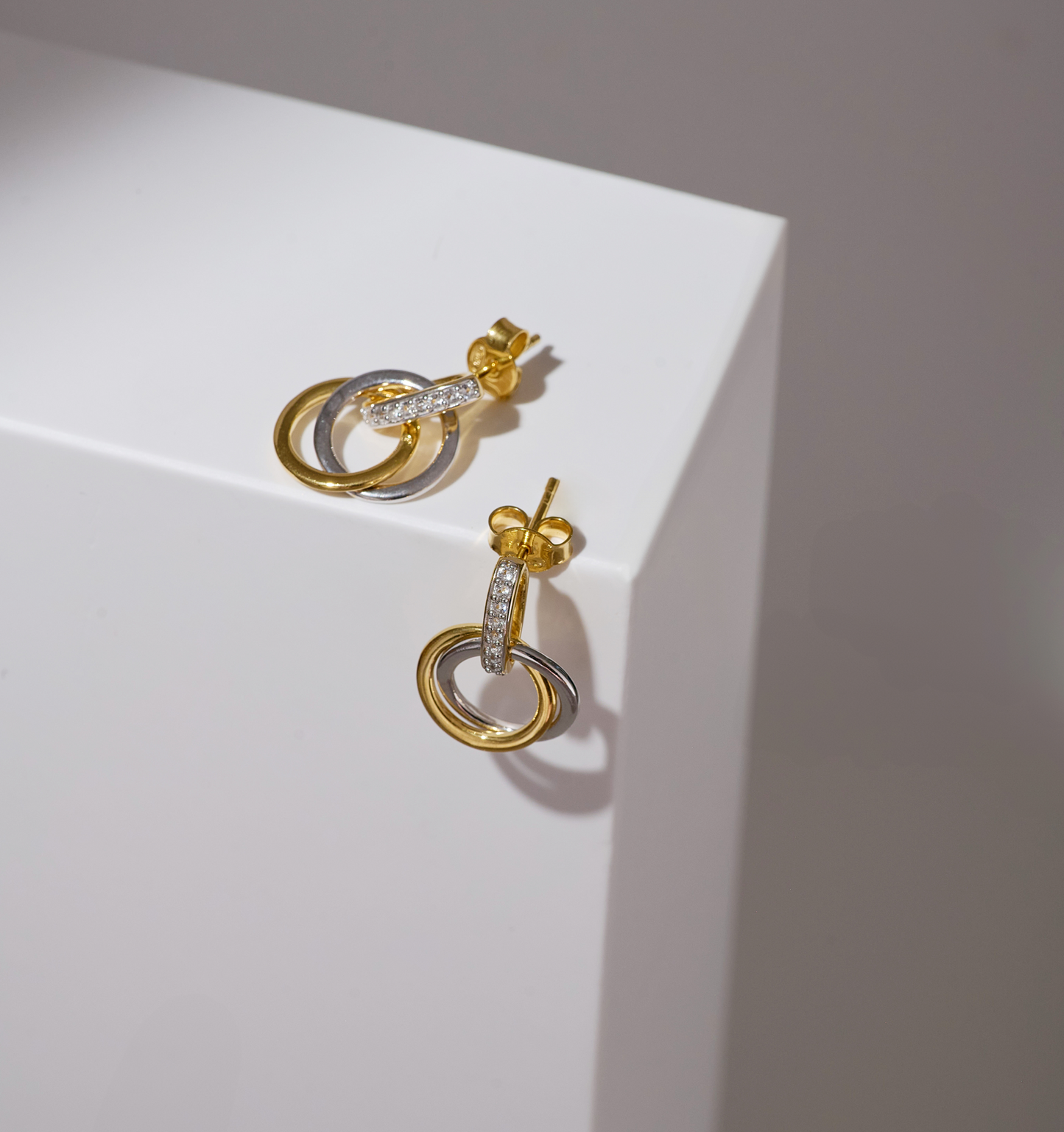 Elegant Nirya Earrings with intertwined gold and silver rings accented with small diamonds