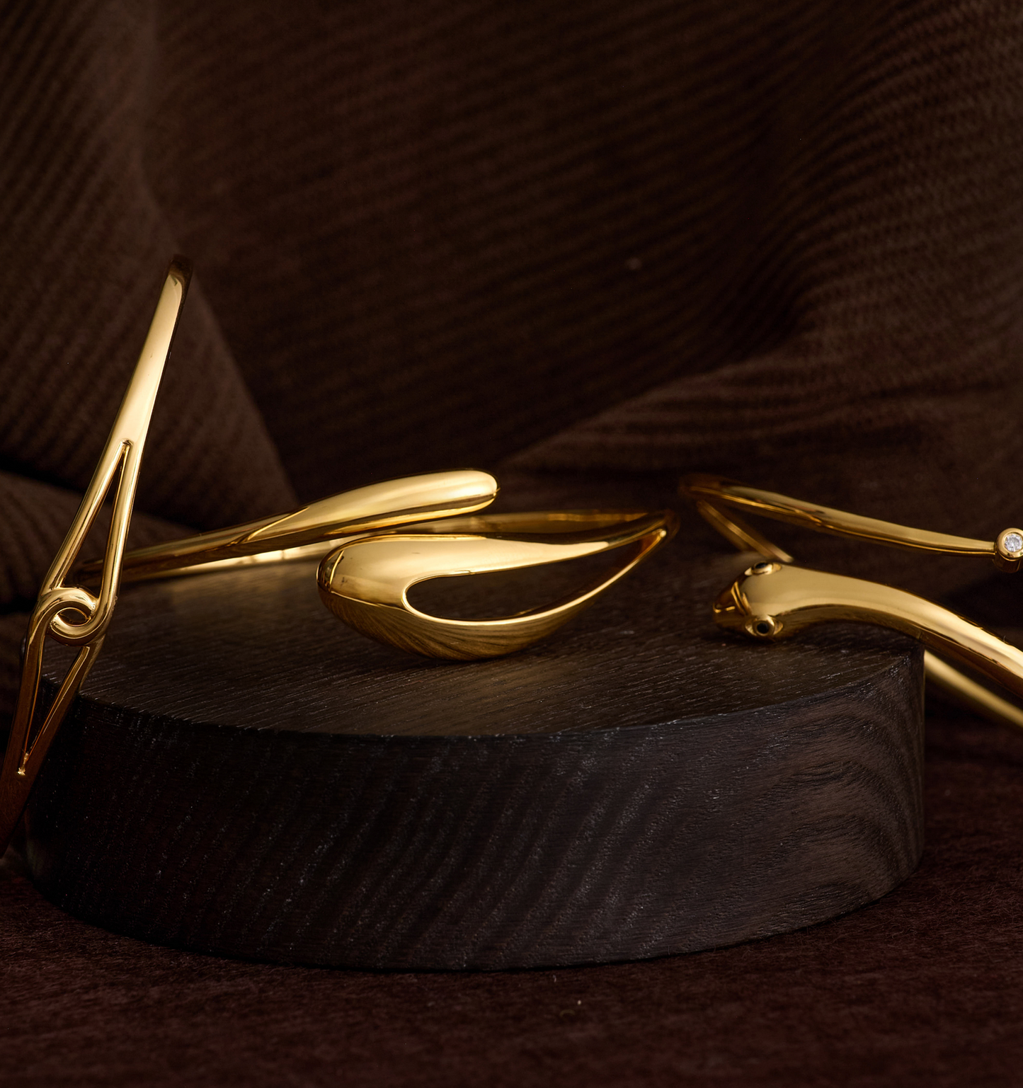 Elegant gold Oriya Cuff with sculptural curved design on dark wooden display