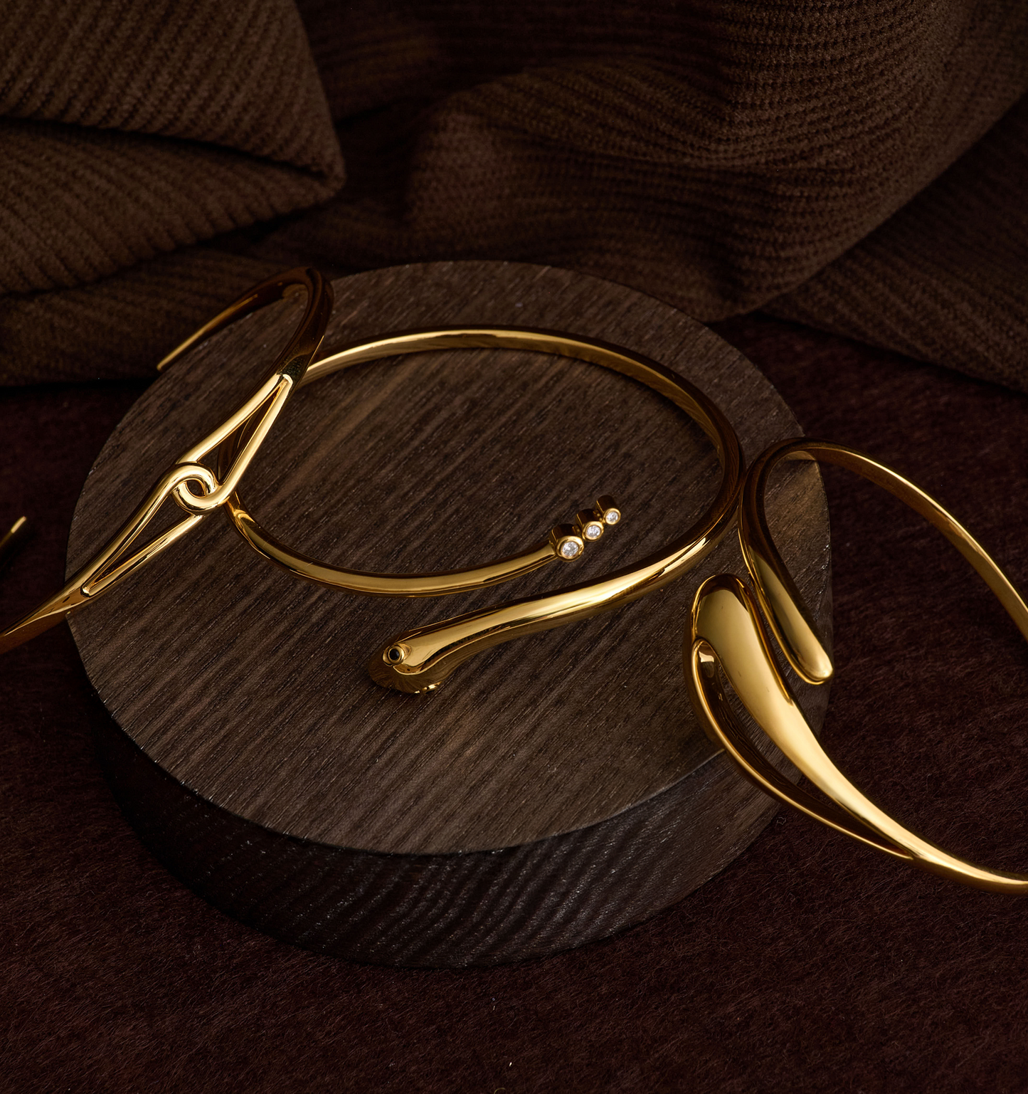 Elegant gold Oriya Cuff with sculptural spiral design on wooden display