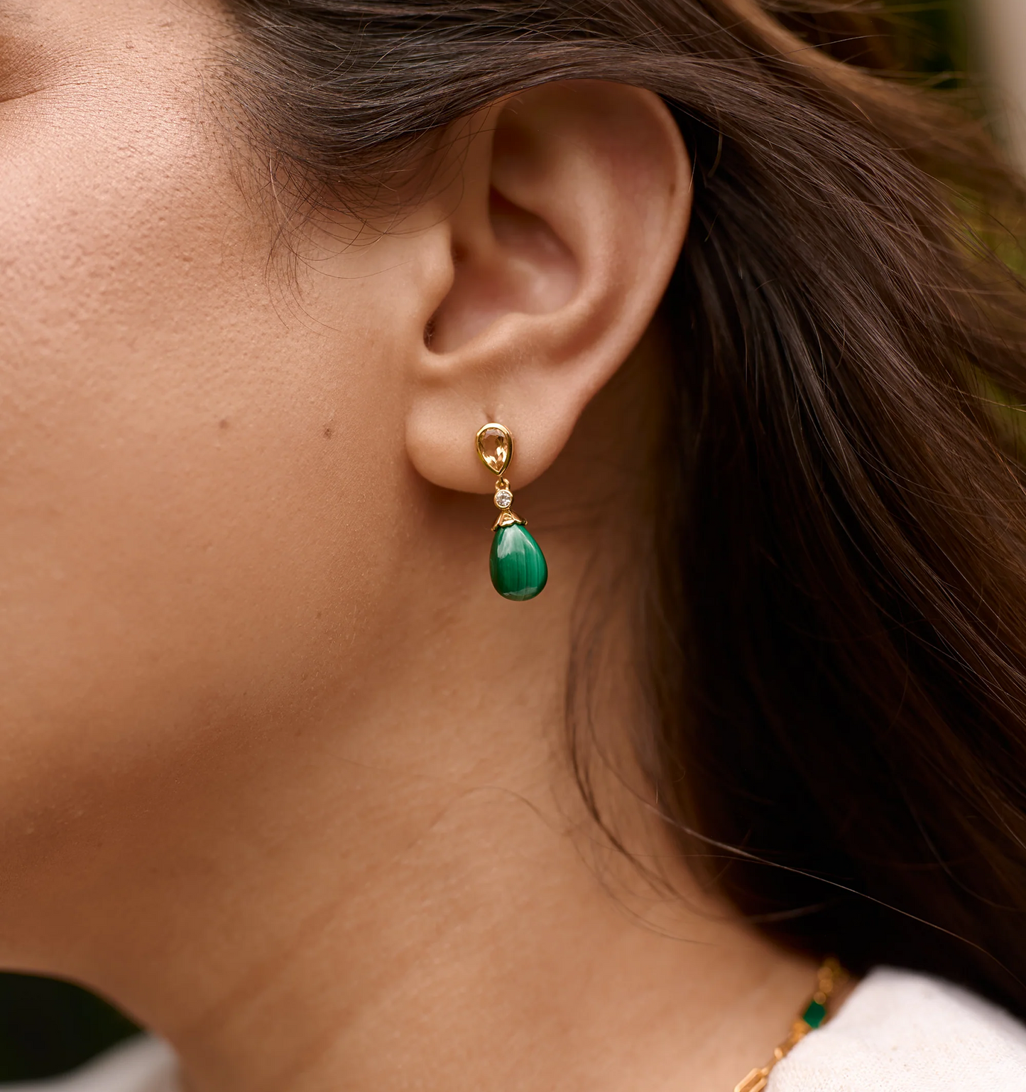 Close-up of ear wearing Triya Earrings featuring green malachite drop and gold setting