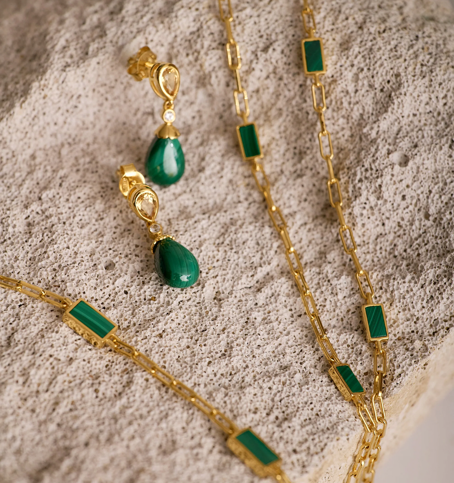 Triya Earrings with green malachite stones and gold accents on textured surface