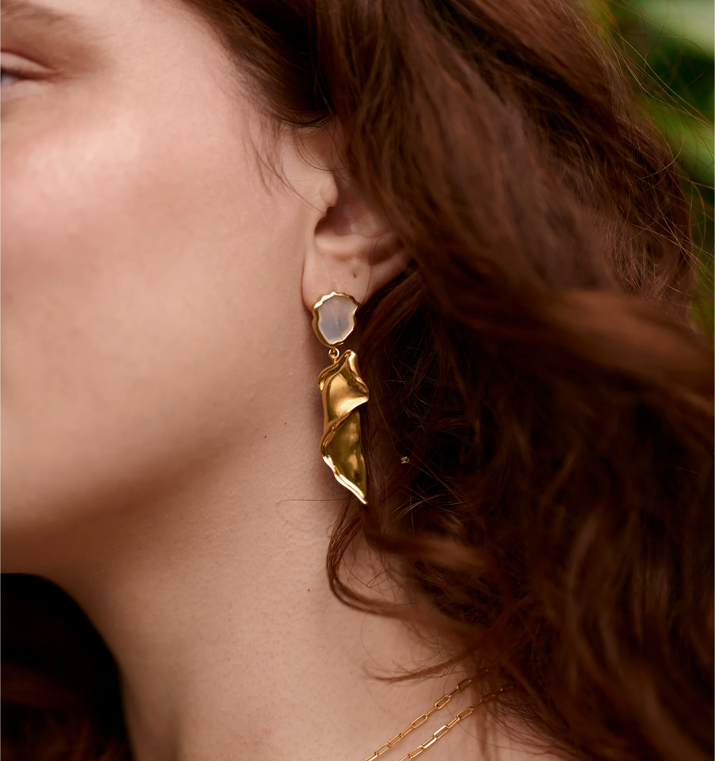 Thalena Earrings gold sculpted cascade with moonstone on woman's ear