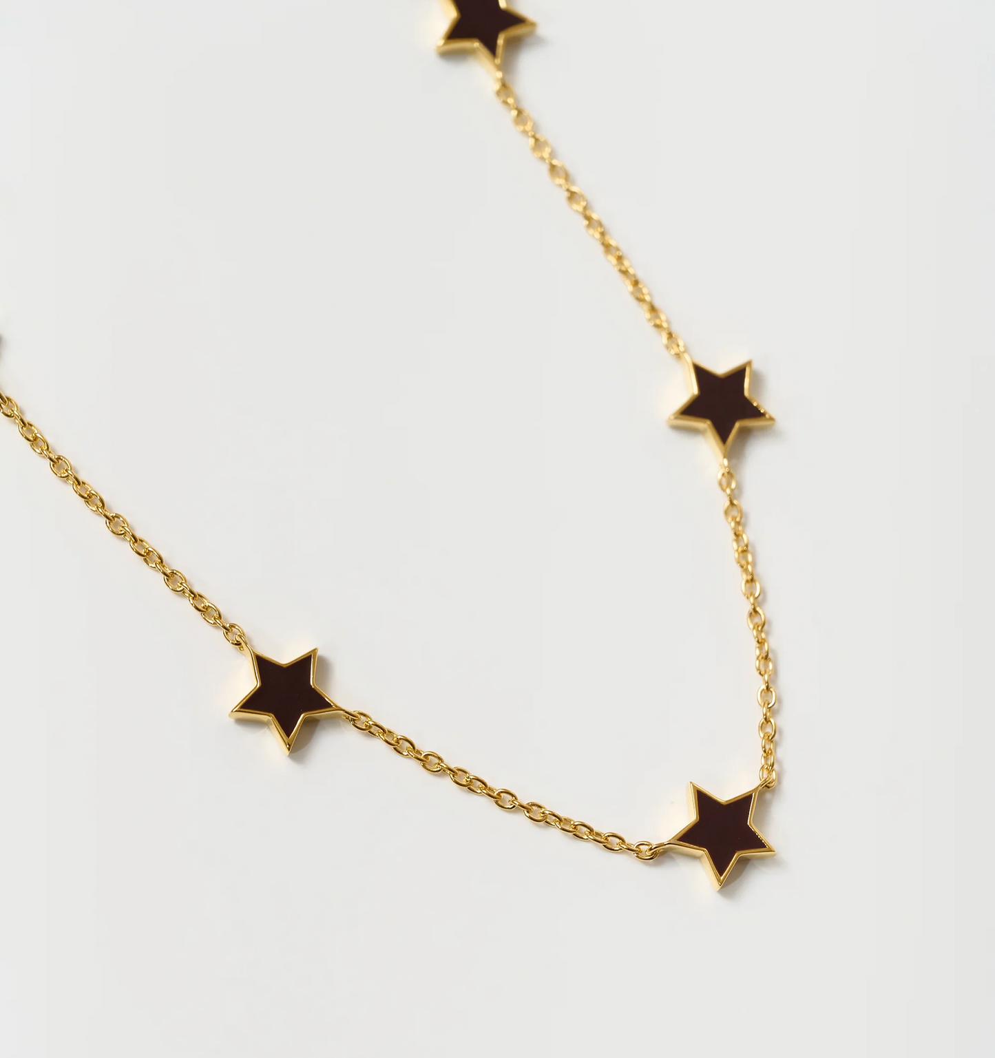 Noctra Necklace gold chain with black star-shaped pendants on white background
