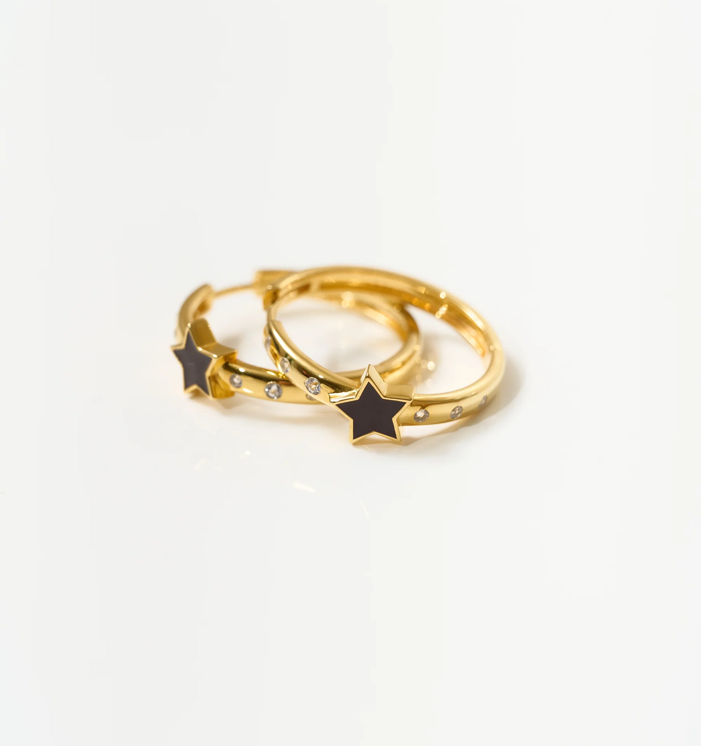 Tara Nova Hoop gold earrings with black star and white topaz stones on white background