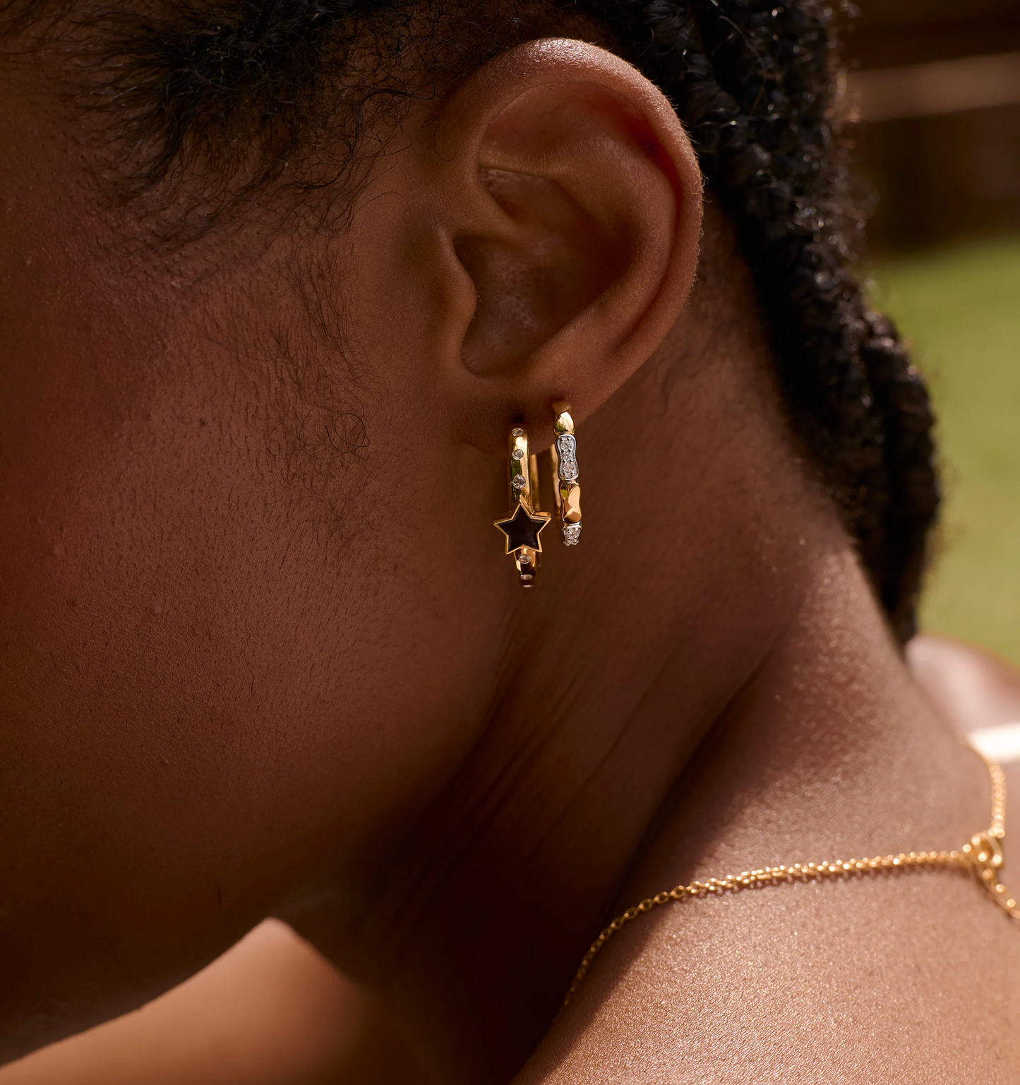 Close-up of ear wearing Tara Nova Hoop gold earrings with white topaz and star design