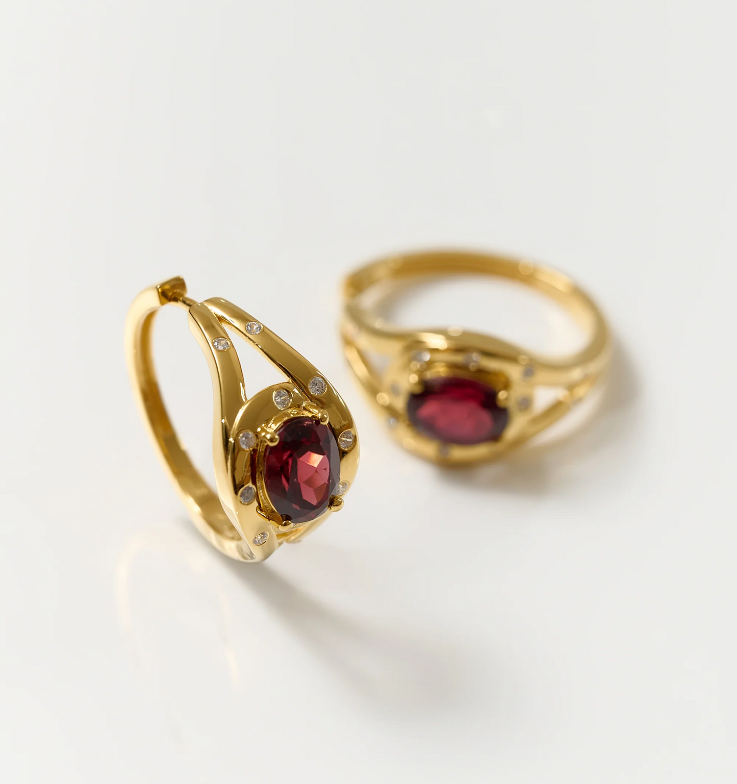 Ruvya Hoops gold earrings with garnet and white zircon gemstones on white background