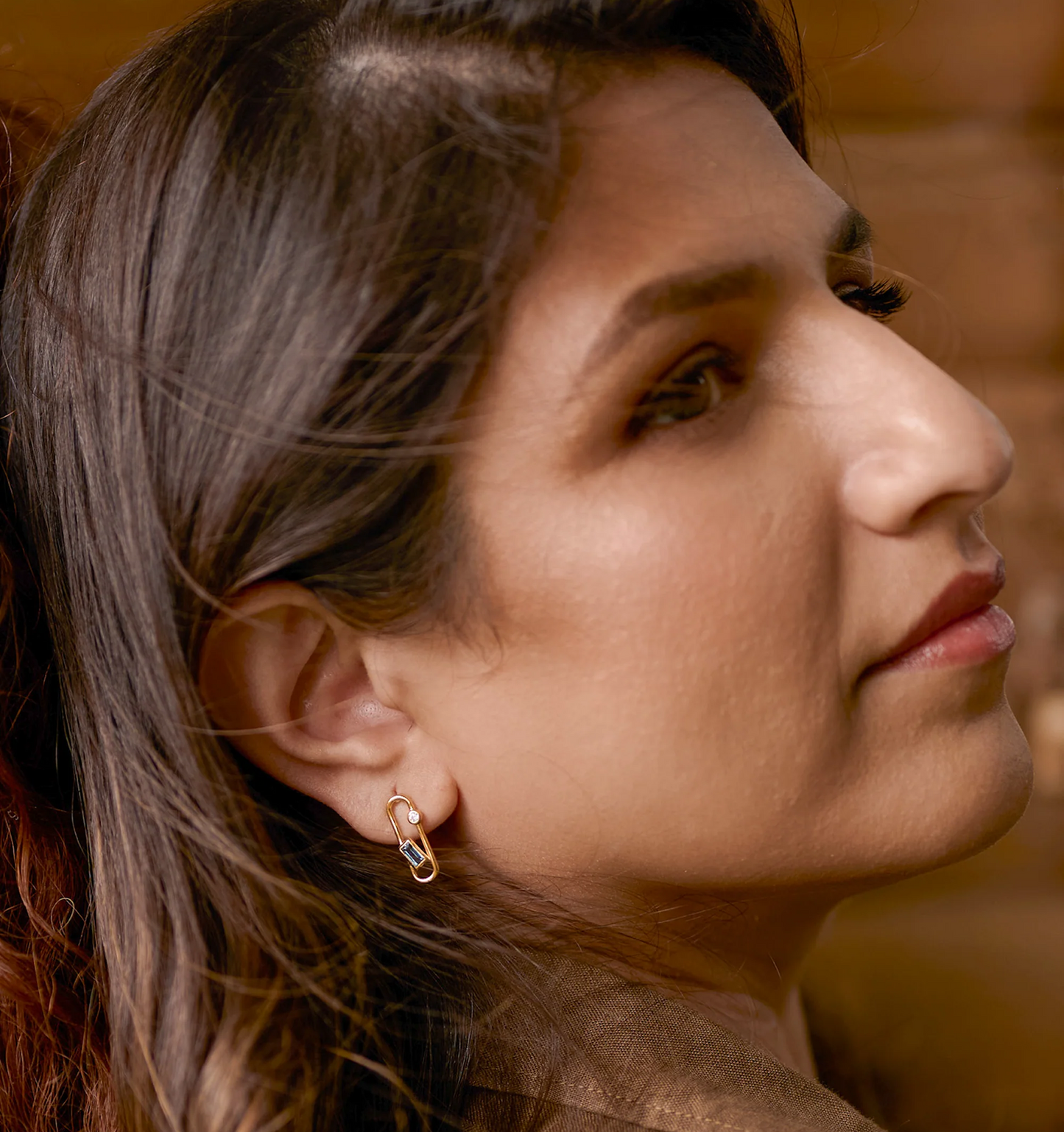 Close-up of a woman wearing elegant Aarka Earrings featuring London Blue Topaz and White Zircon for radiant, silent strength.