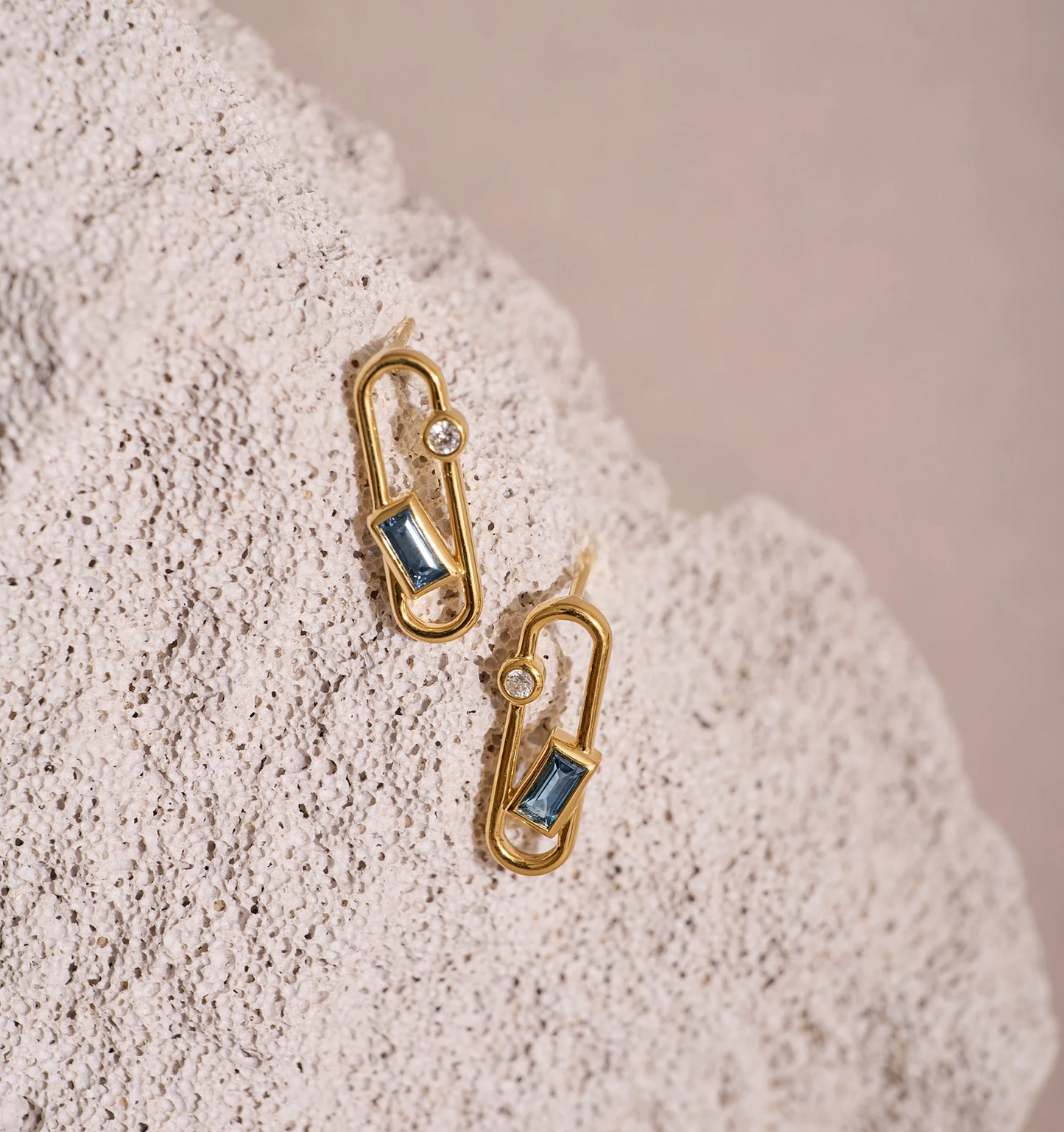 Aarka Earrings gold with London Blue Topaz and White Zircon gemstones on textured background