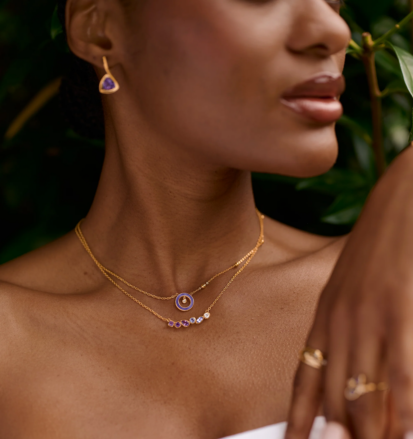 Raag Necklace with layered gold chains featuring amethyst and tanzanite gemstones on a woman