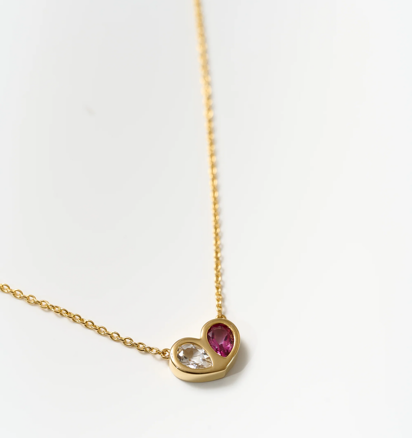 Manas Necklace gold chain with heart-shaped pendant featuring twin red and clear stones symbolizing harmony.