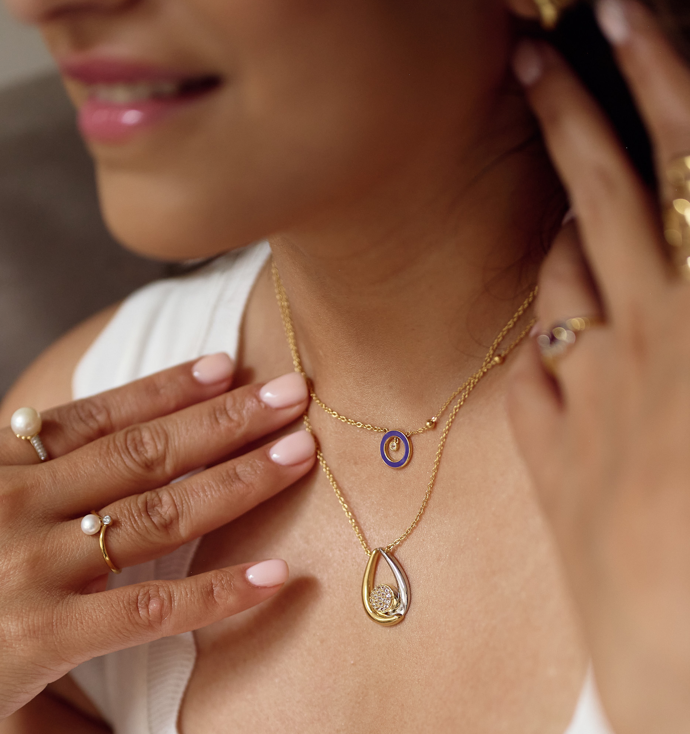 Antara Necklace with twin gold and silver arcs featuring 19 white topaz stones on a woman’s neck