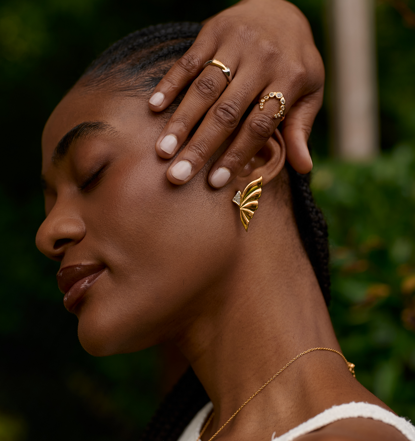 Close-up of a woman wearing gold Elara Earrings shaped like butterfly wings with layered curves.