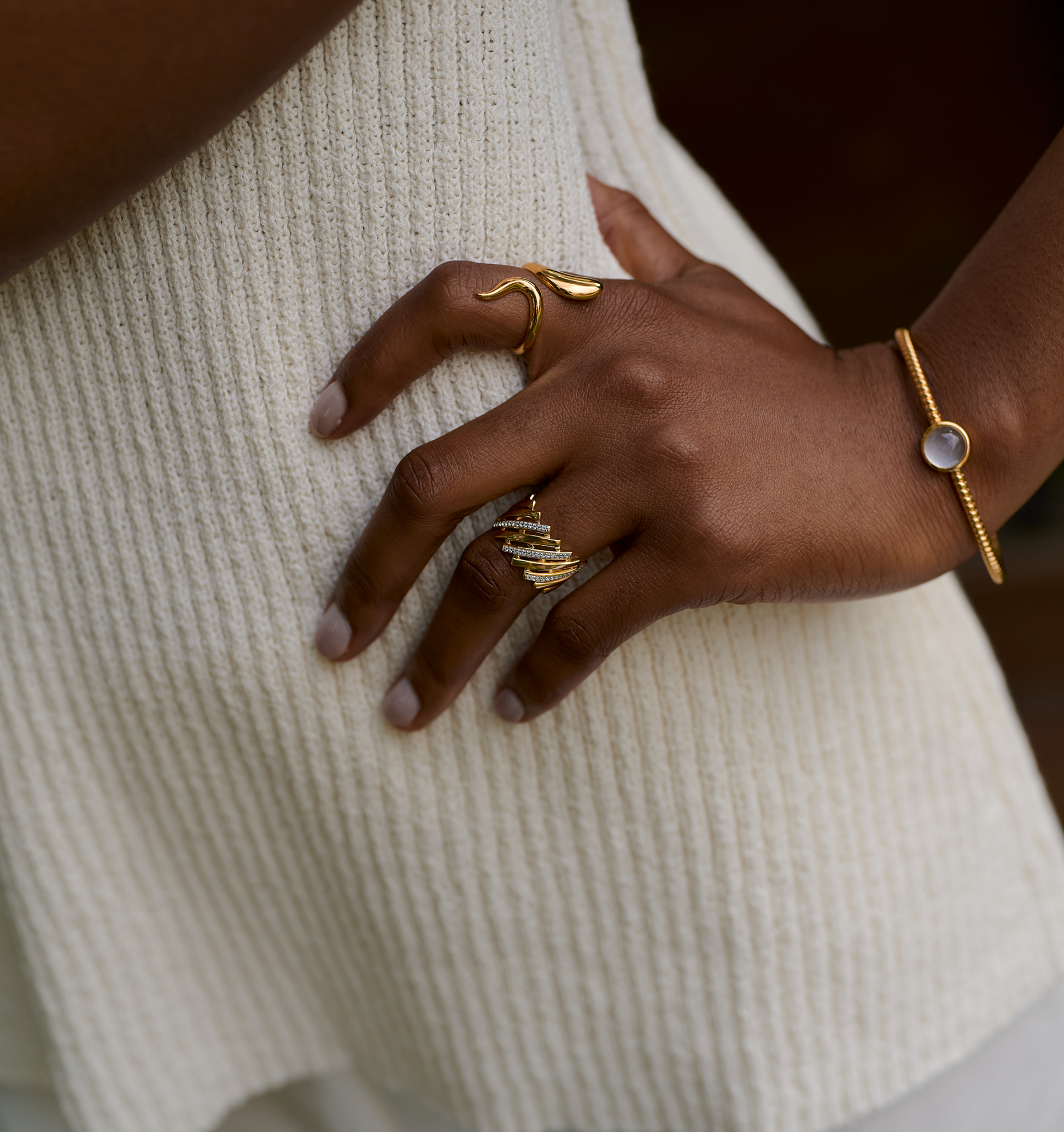 Gold Reya Ring with chevron curves and white topaz stones on hand