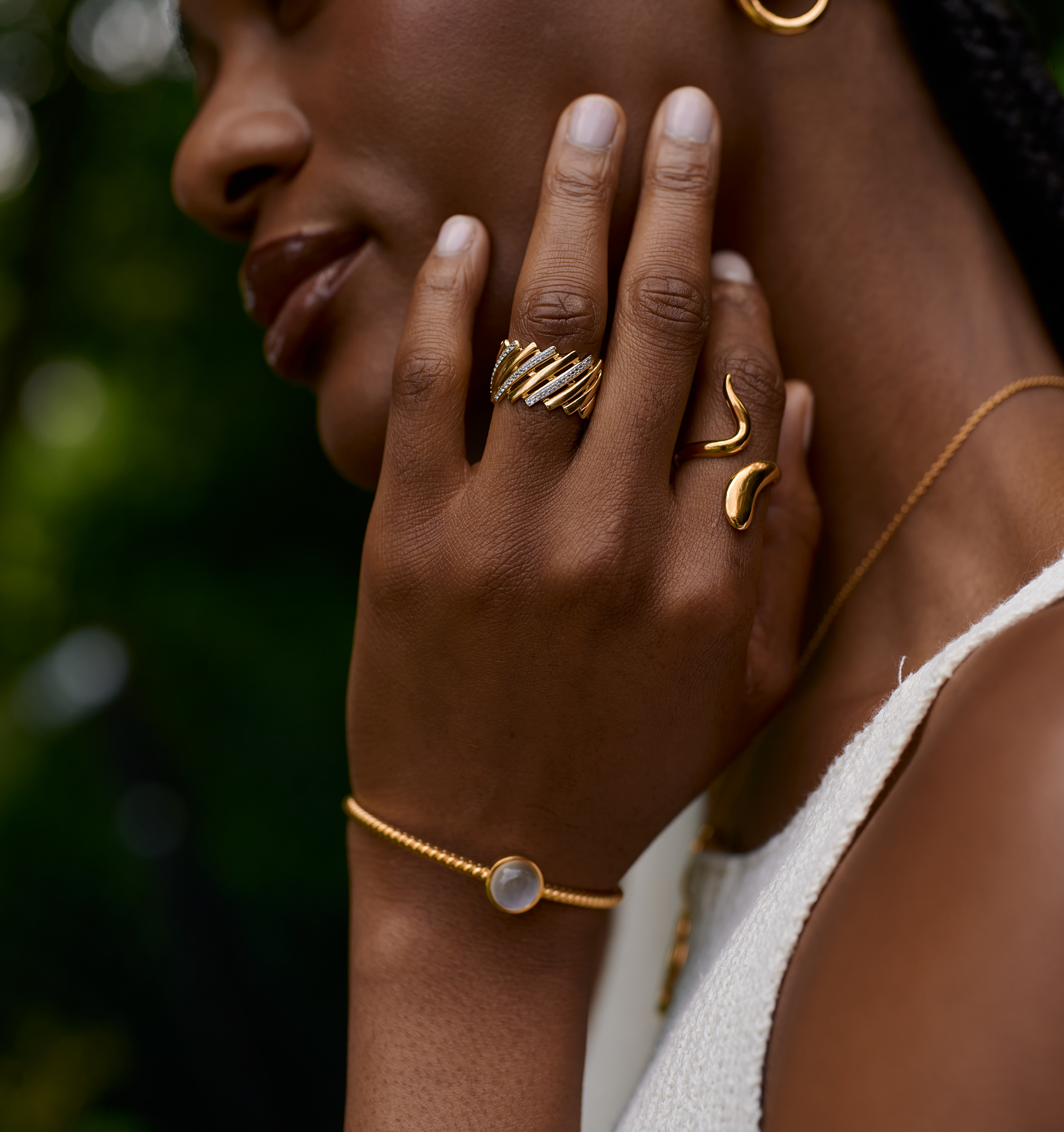 Woman wearing gold Tarini Cuff bracelet with moonstone, gold rings, and necklace showcasing elegant feminine jewelry