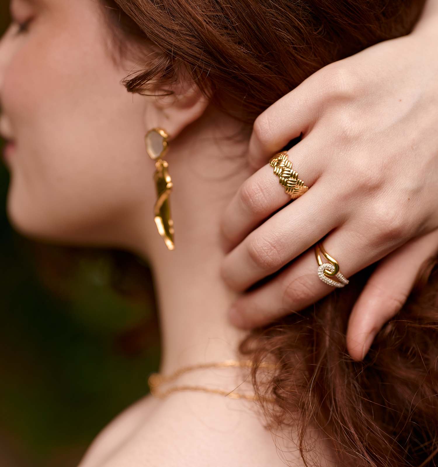 Close-up of a woman's hand wearing a gold Kaari Ring with intricate weaving detail