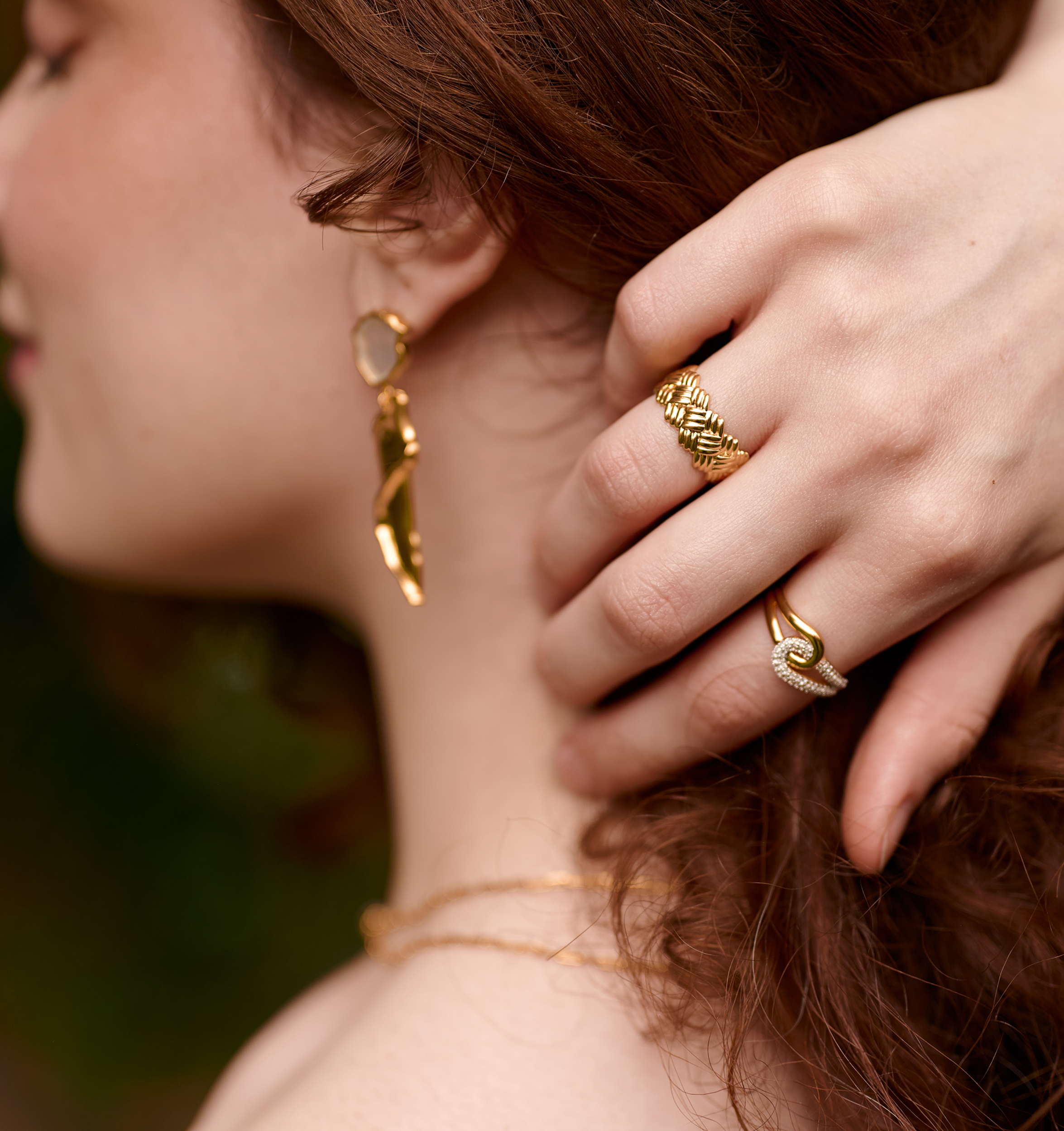 Close-up of a woman's hand wearing a gold Kaari Ring with intricate weaving detail