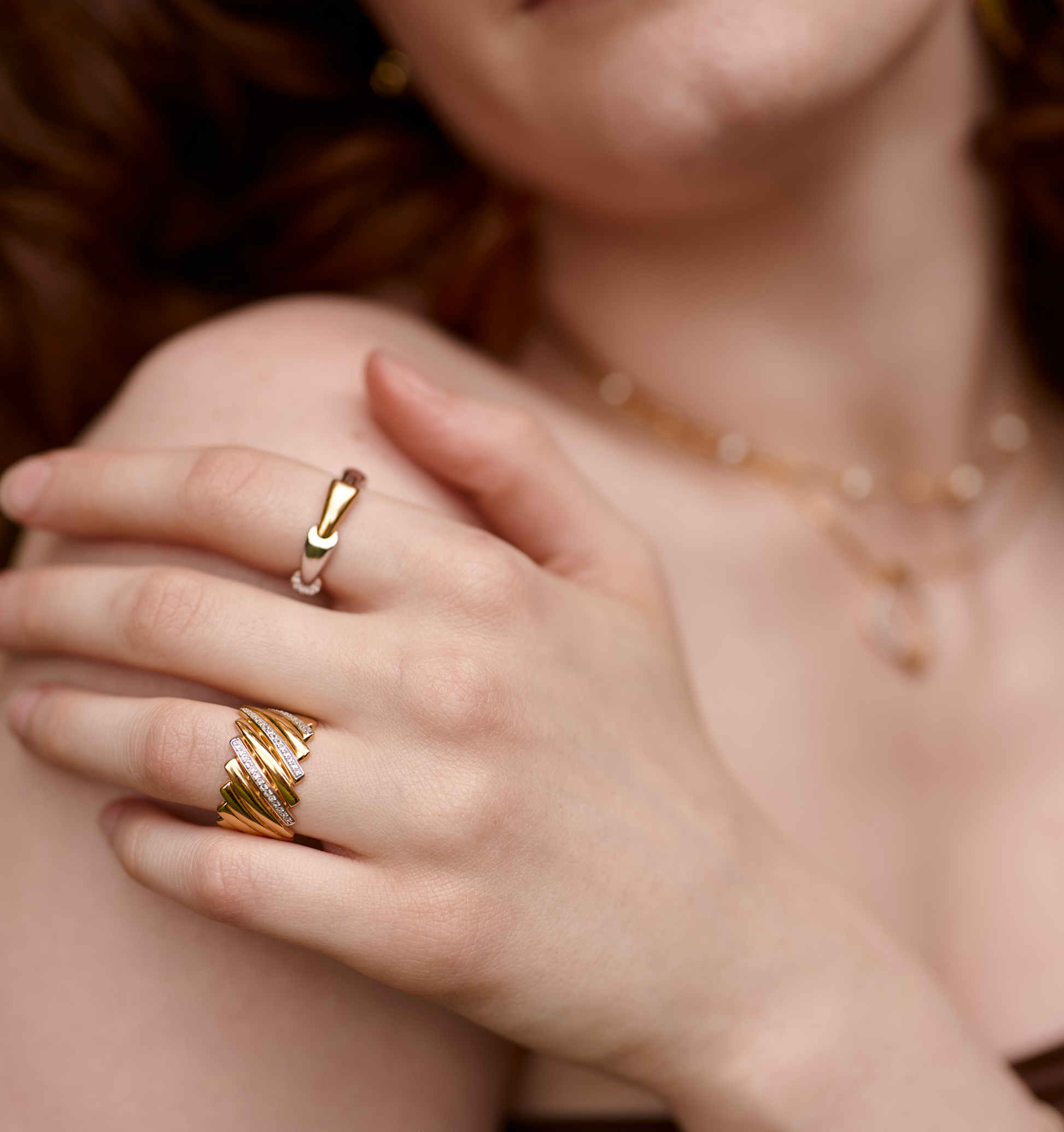 Close-up of Reya Ring with gold chevron curves and white topaz stones on woman's hand