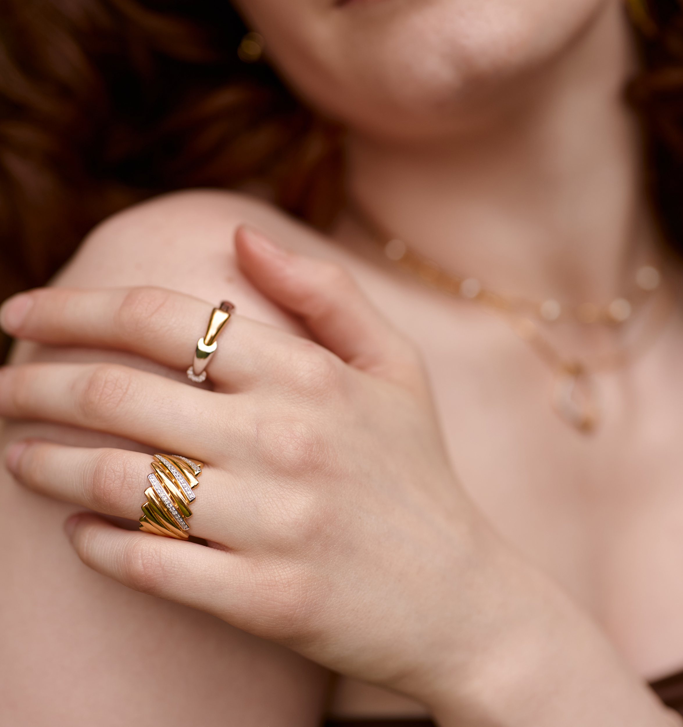 Close-up of Reya Ring with gold chevron curves and white topaz stones on woman's hand