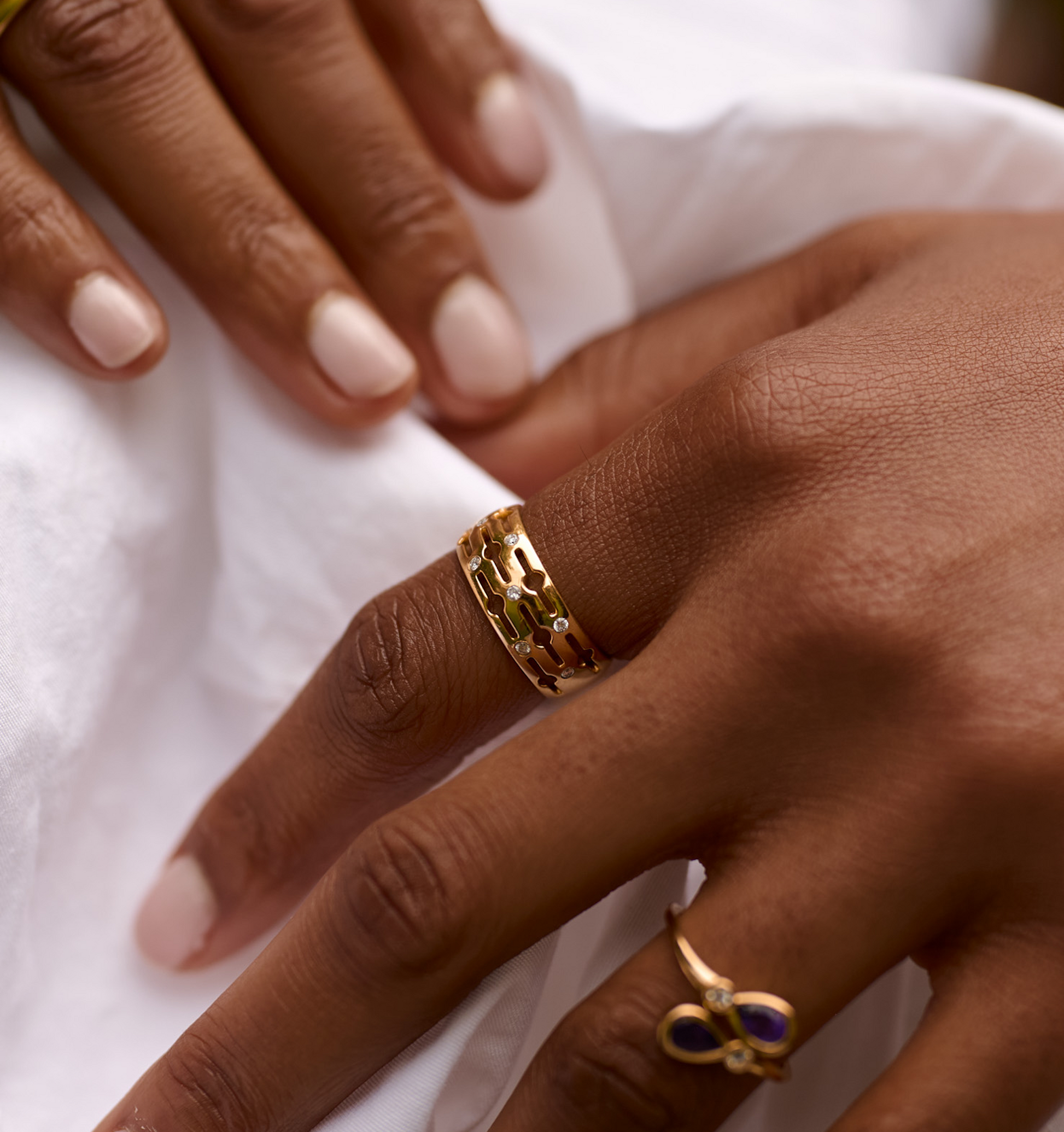 Close-up of a hand wearing a gold Svar Ring with intricate design and diamonds on the finger.