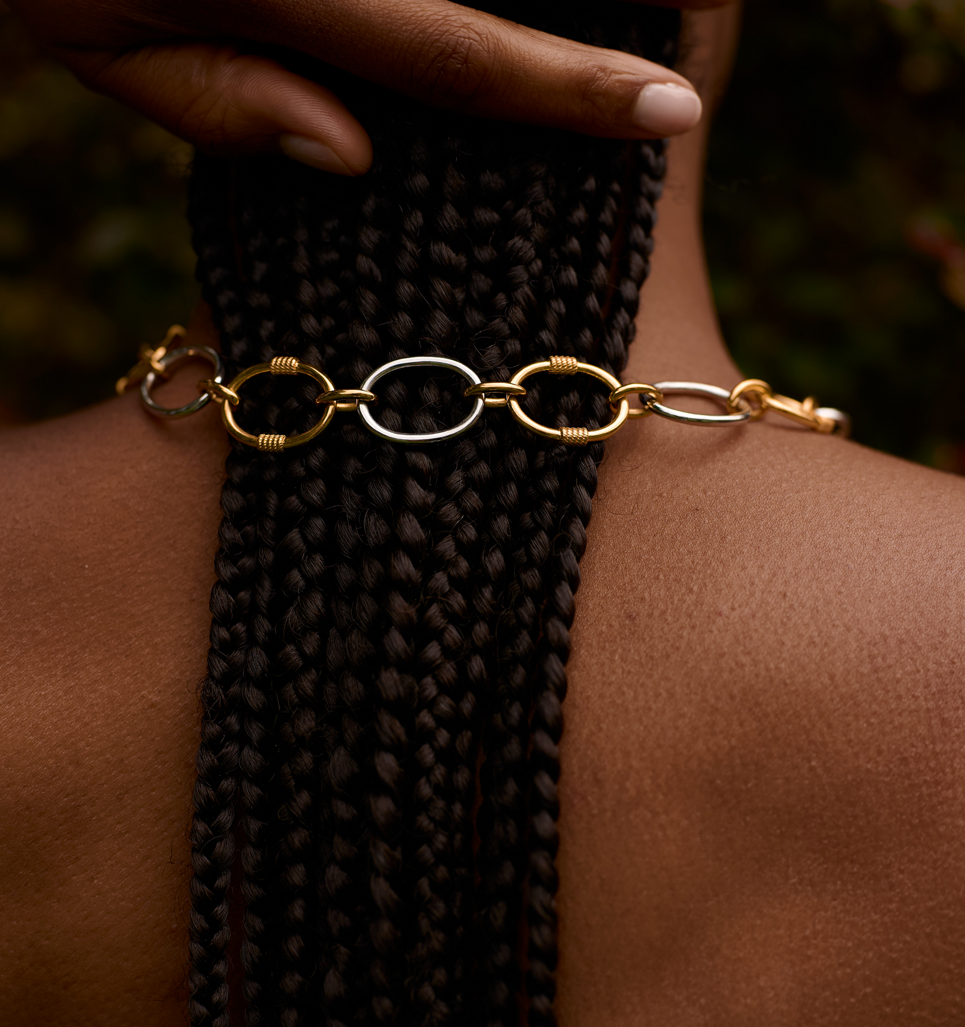 Close-up of Tasya Necklace with gold and silver interlocking links on braided hair.