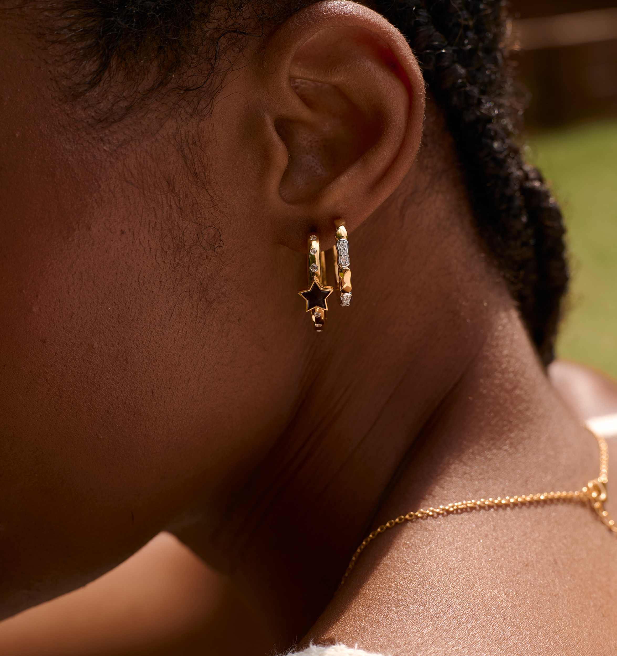 Close-up of ear wearing Orita Earrings with gold and silver tones and star charm design