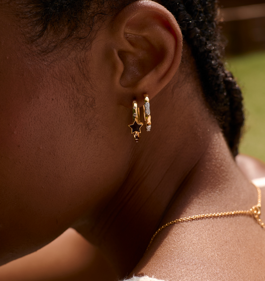Close-up of ear wearing Orita Earrings with gold and silver tones and star charm design