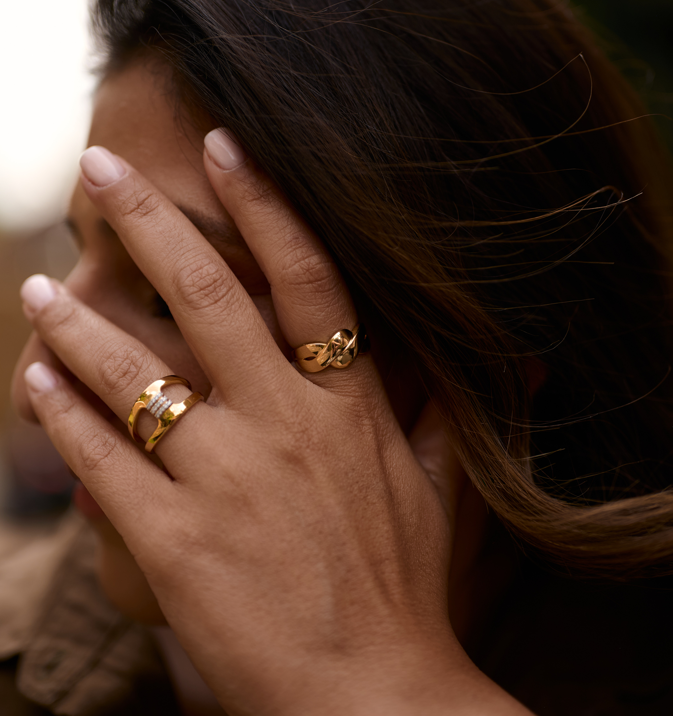 Close-up of a hand wearing two gold Niva Rings symbolizing fluid and eternal presence