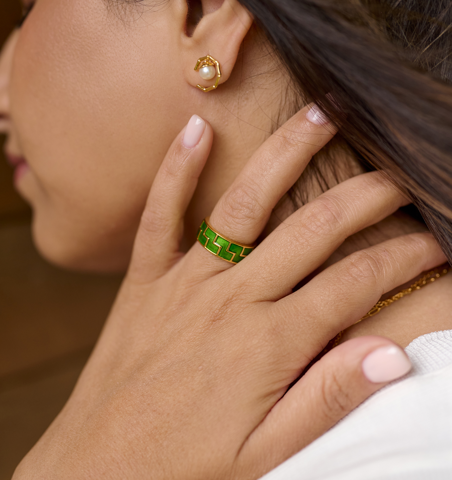Close-up of Kavach Earrings with pearl detail worn on ear, paired with a green enamel ring and soft pink nail polish