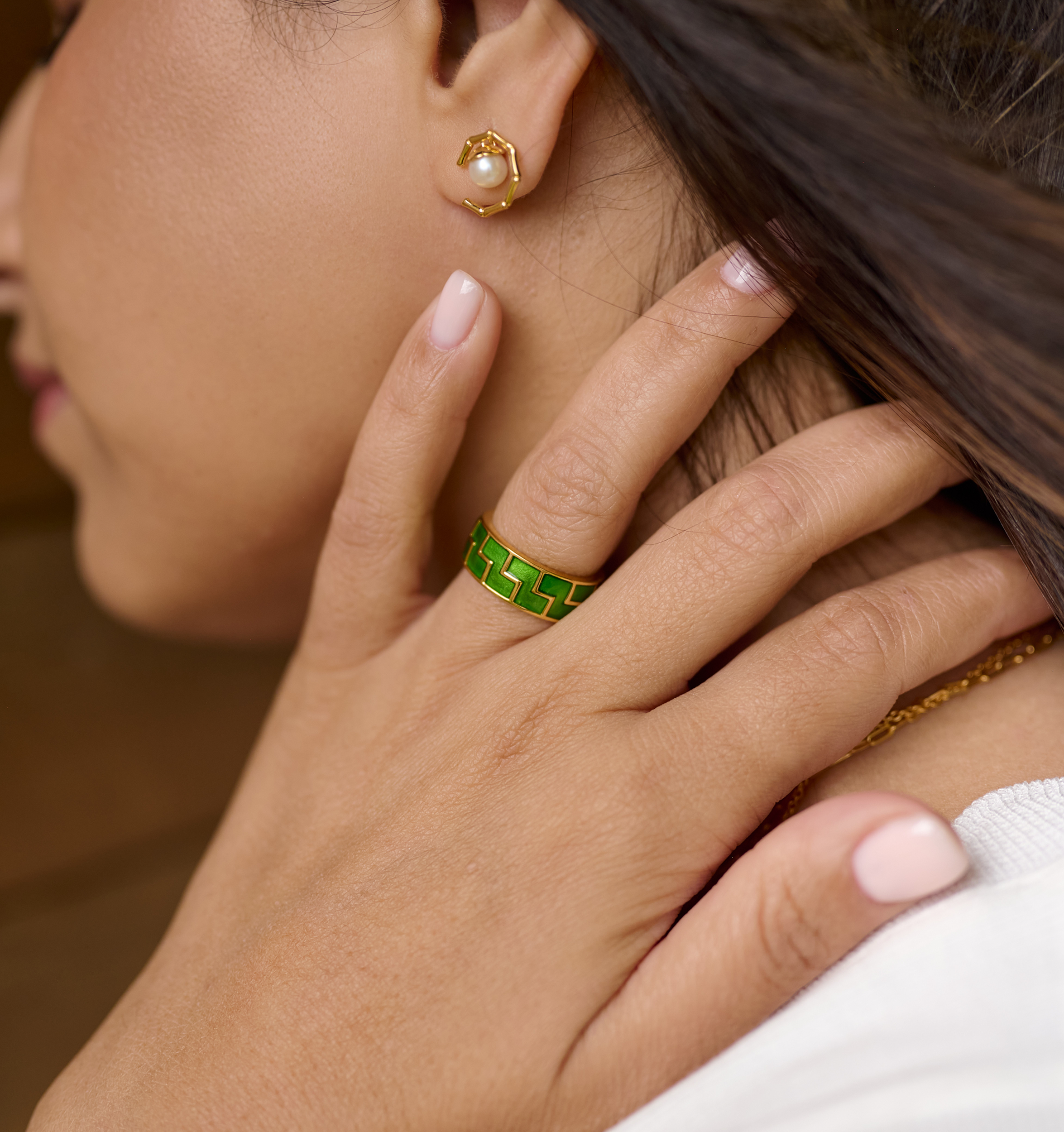 Close-up of Kavach Earrings with pearl detail worn on ear, paired with a green enamel ring and soft pink nail polish