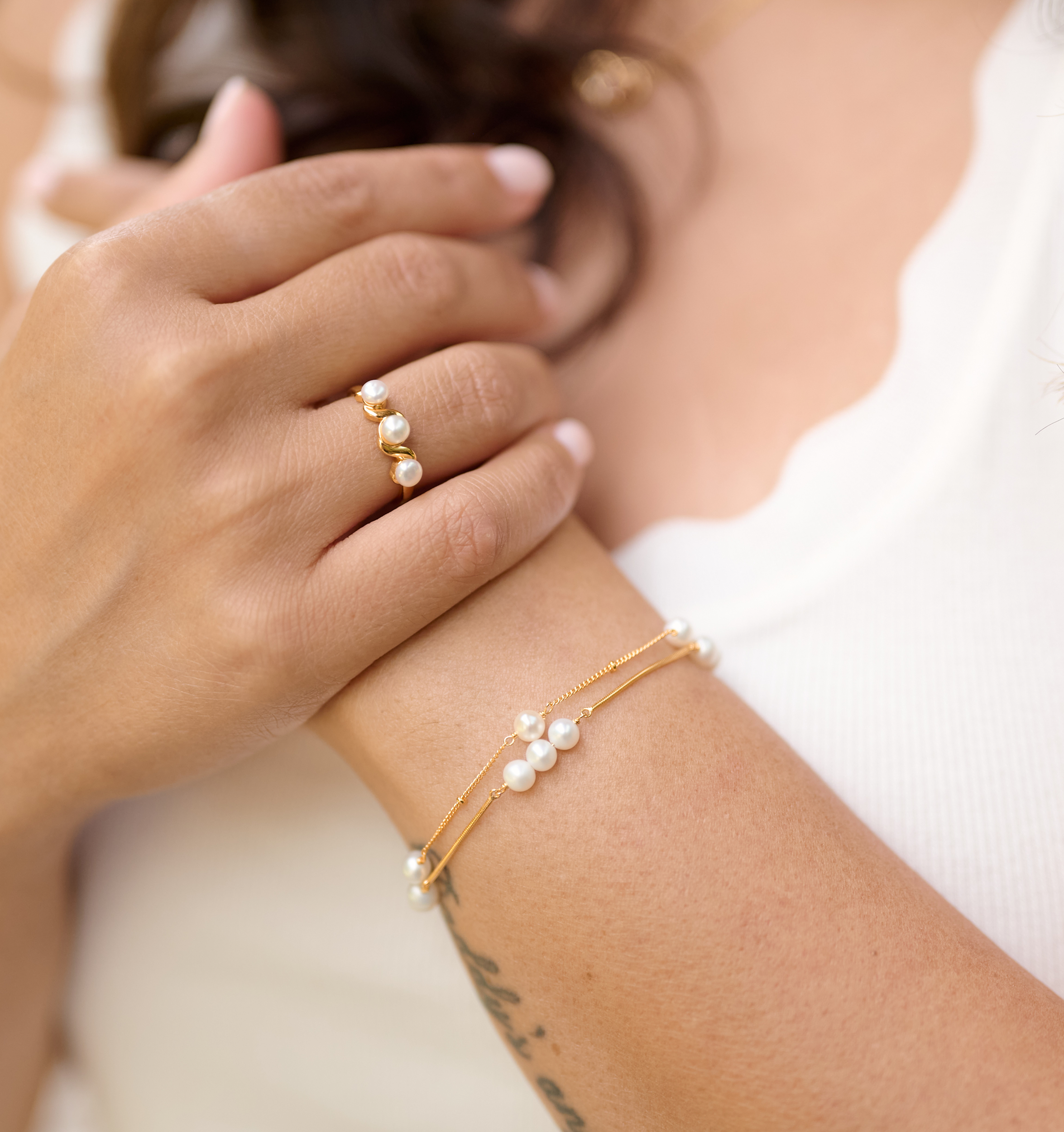 Close-up of Kanik Bracelet with pearls and gold on wrist and matching pearl gold ring on finger