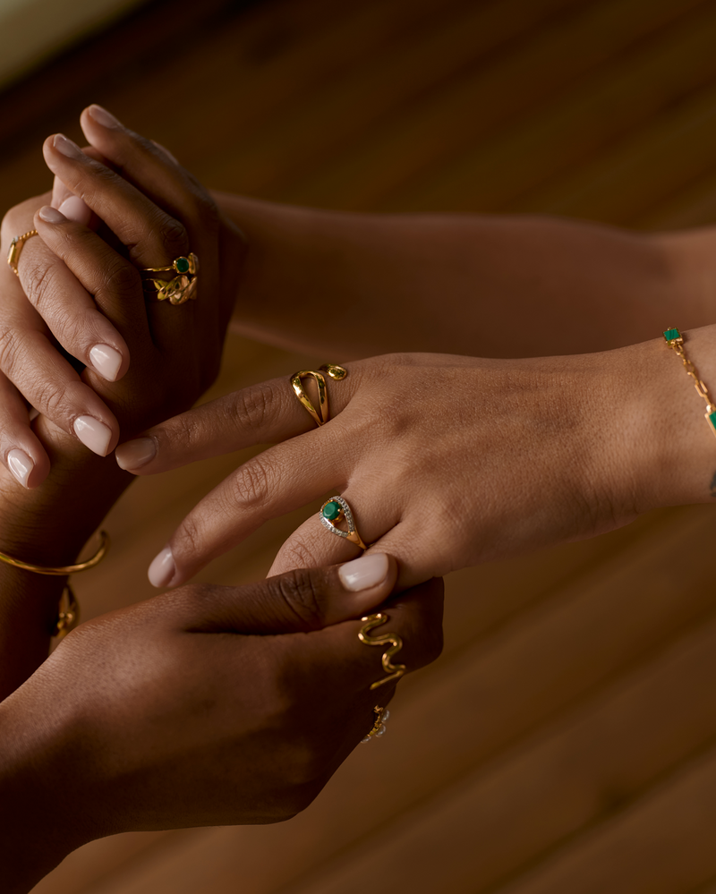 Saena Ring gold jewelry with green stone worn on hand showcasing elegant protective design