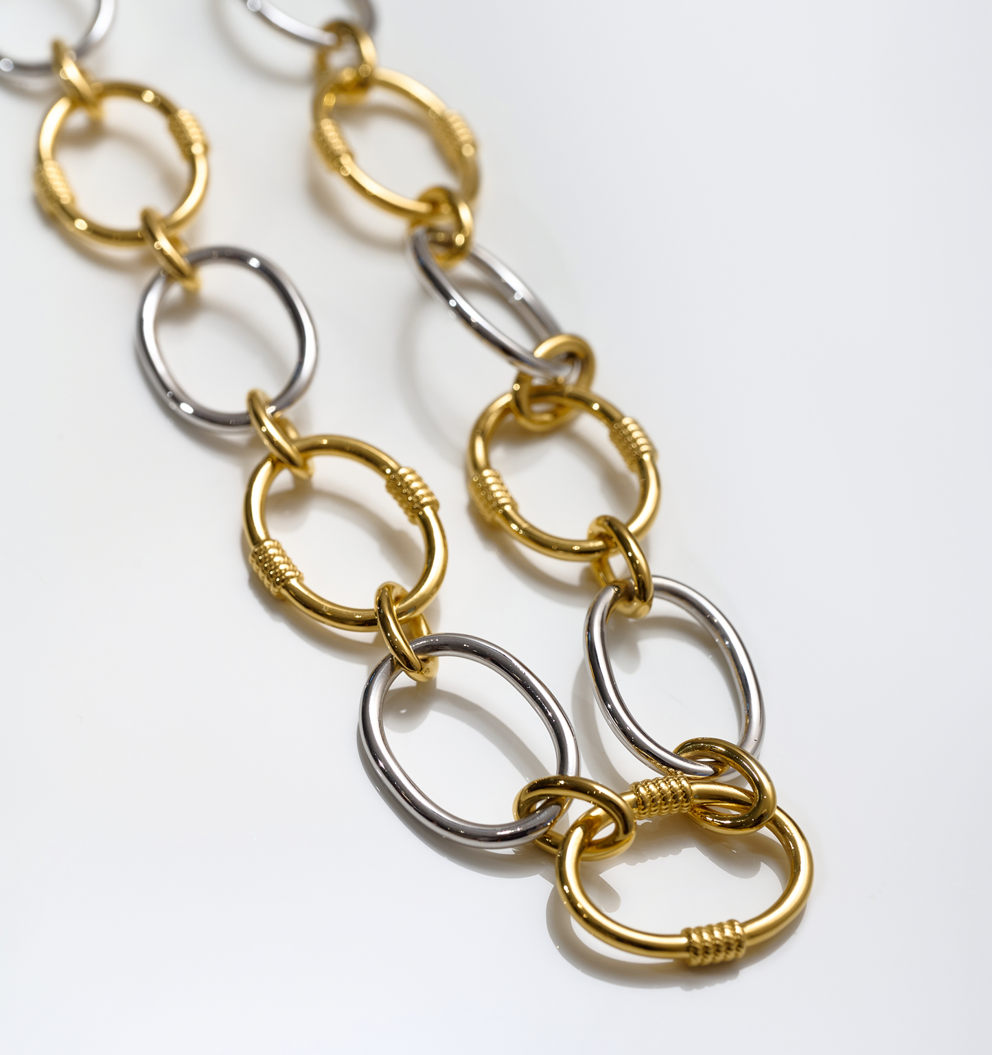 Close-up of Tasya Necklace featuring alternating gold and silver linked rings with textured details