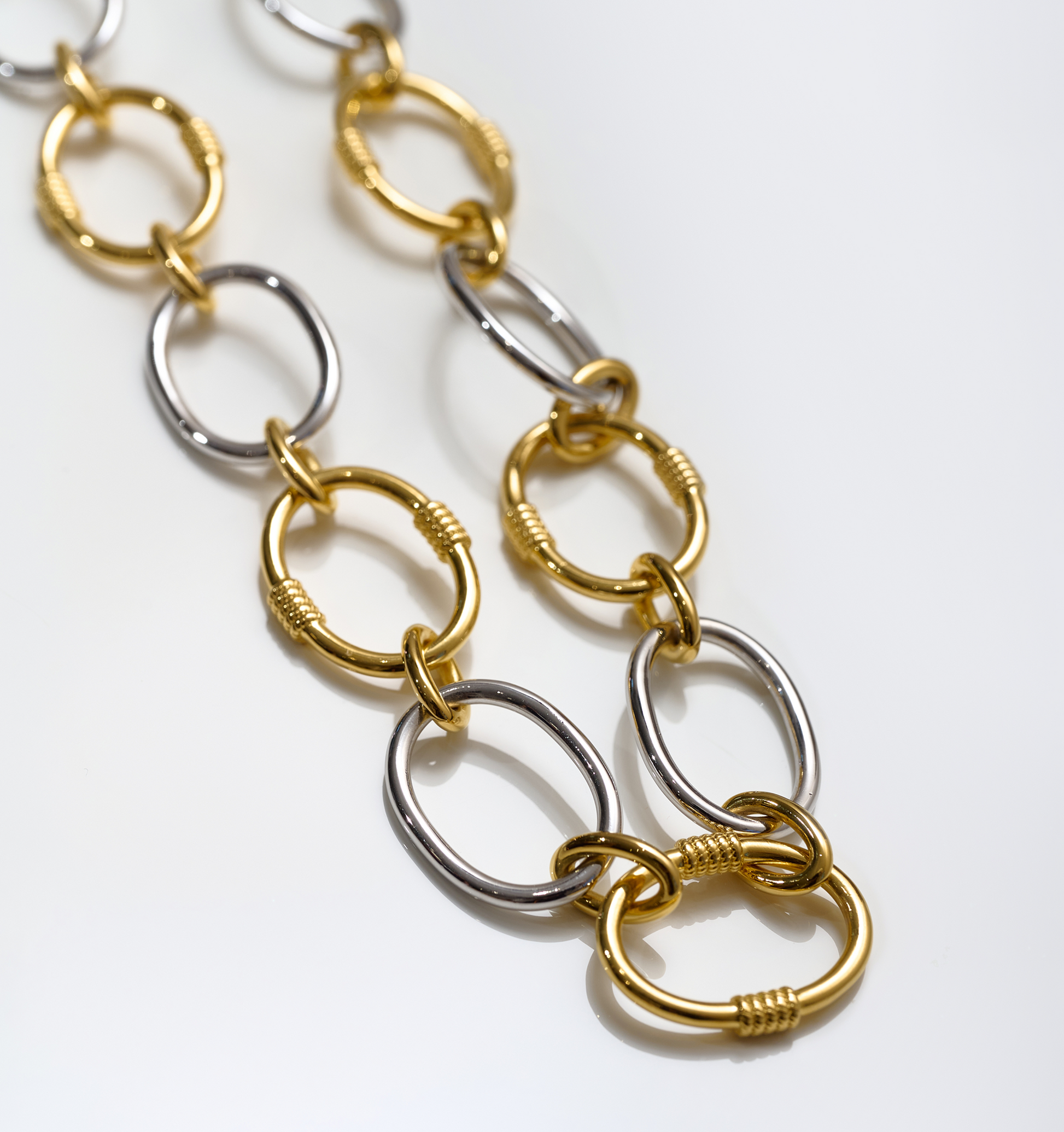 Close-up of Tasya Necklace featuring alternating gold and silver linked rings with textured details