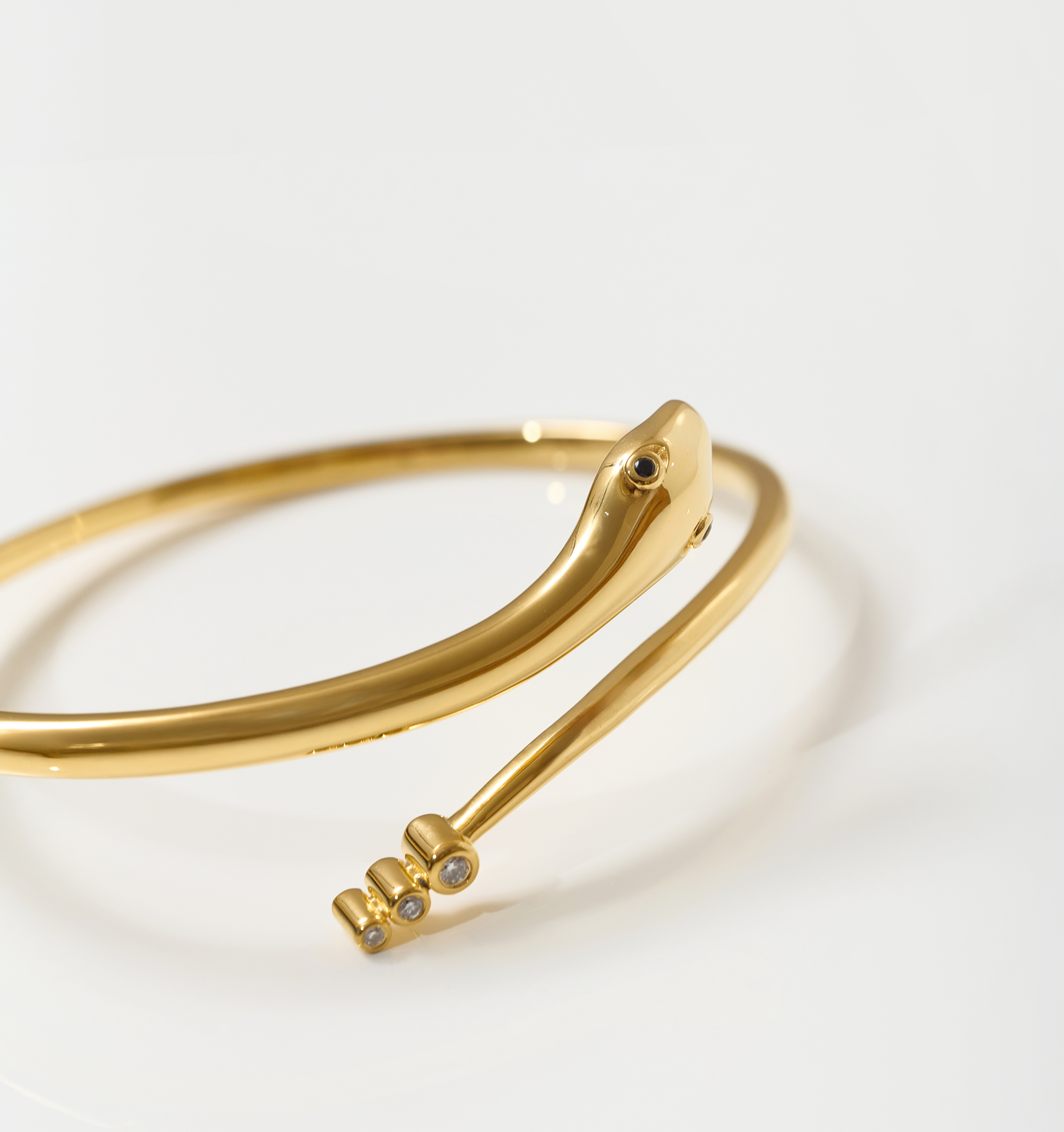 Gold Sarpa Cuff bracelet with serpent design, black spinel eyes, and diamond accents