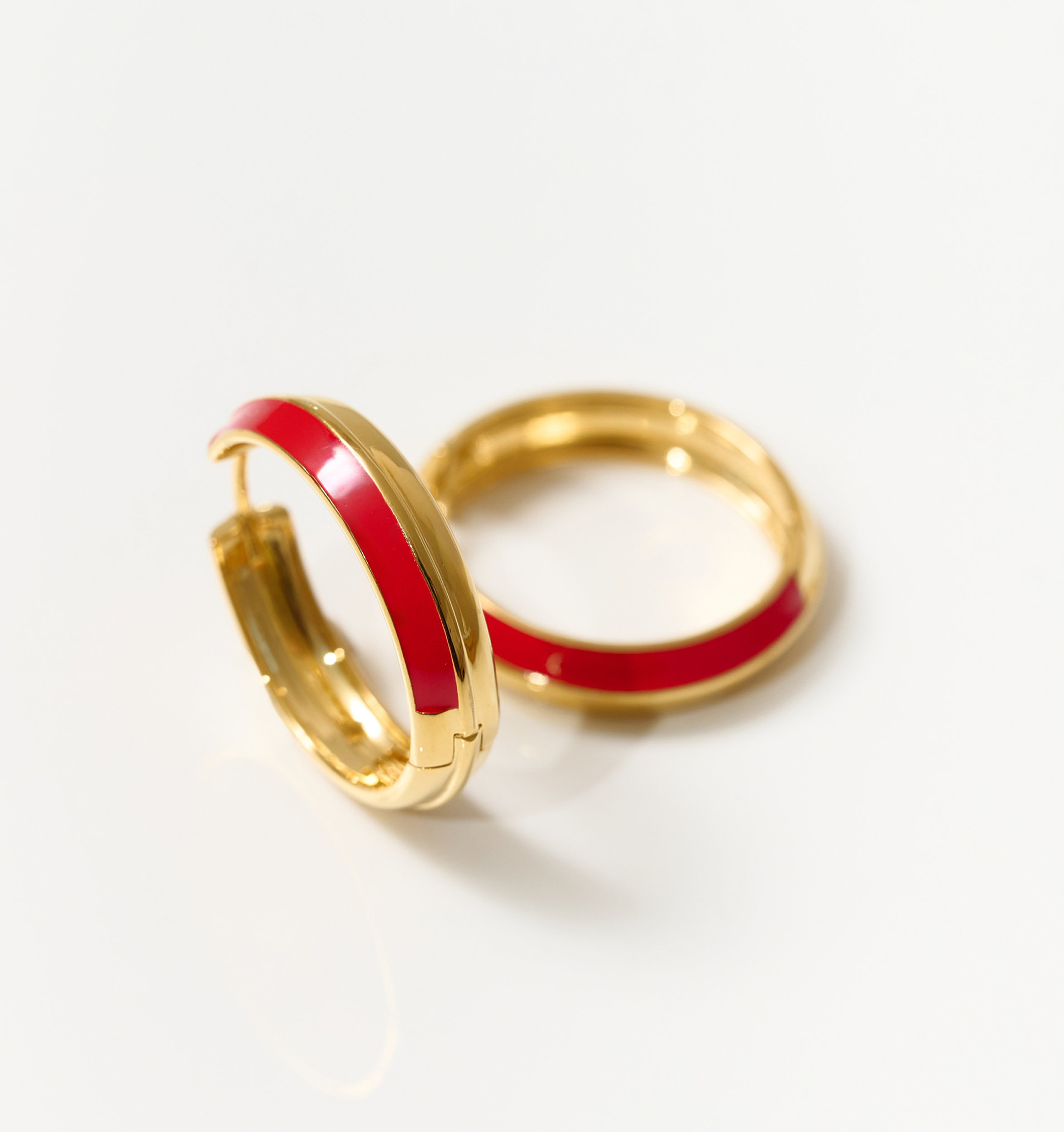 Gold hoop earrings with deep red enamel detailing called Rati Hoop, symbolizing feminine strength and elegance.