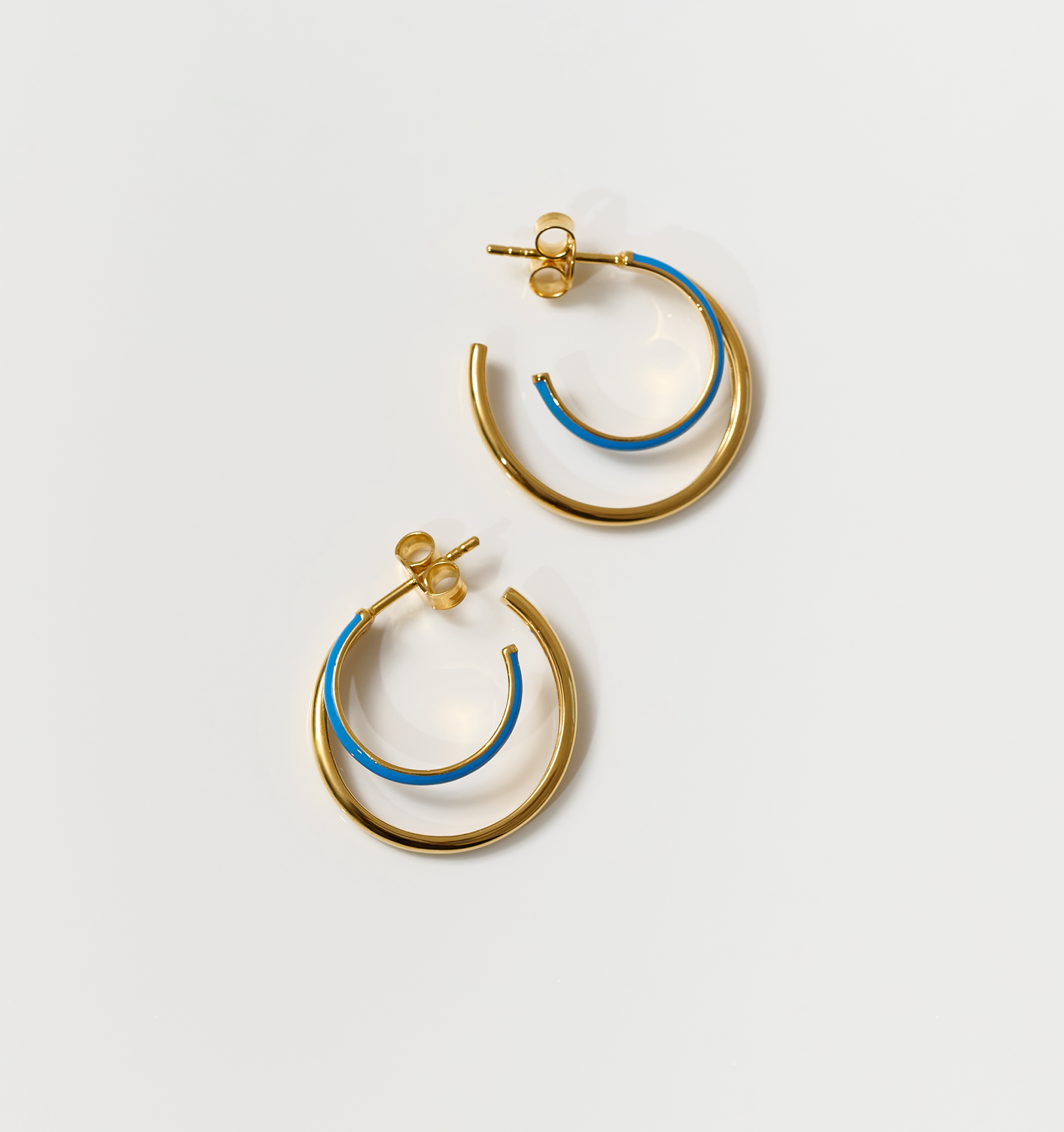 Pair of Soma Hoops with gold and turquoise enamel crescent design on white background