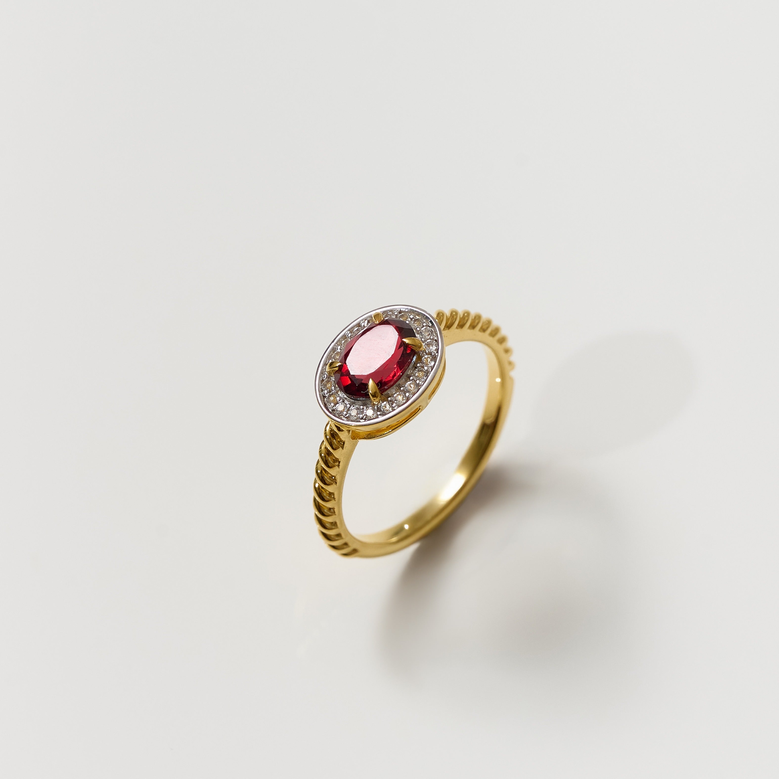 Agira Ring gold band with central garnet surrounded by white topaz halo