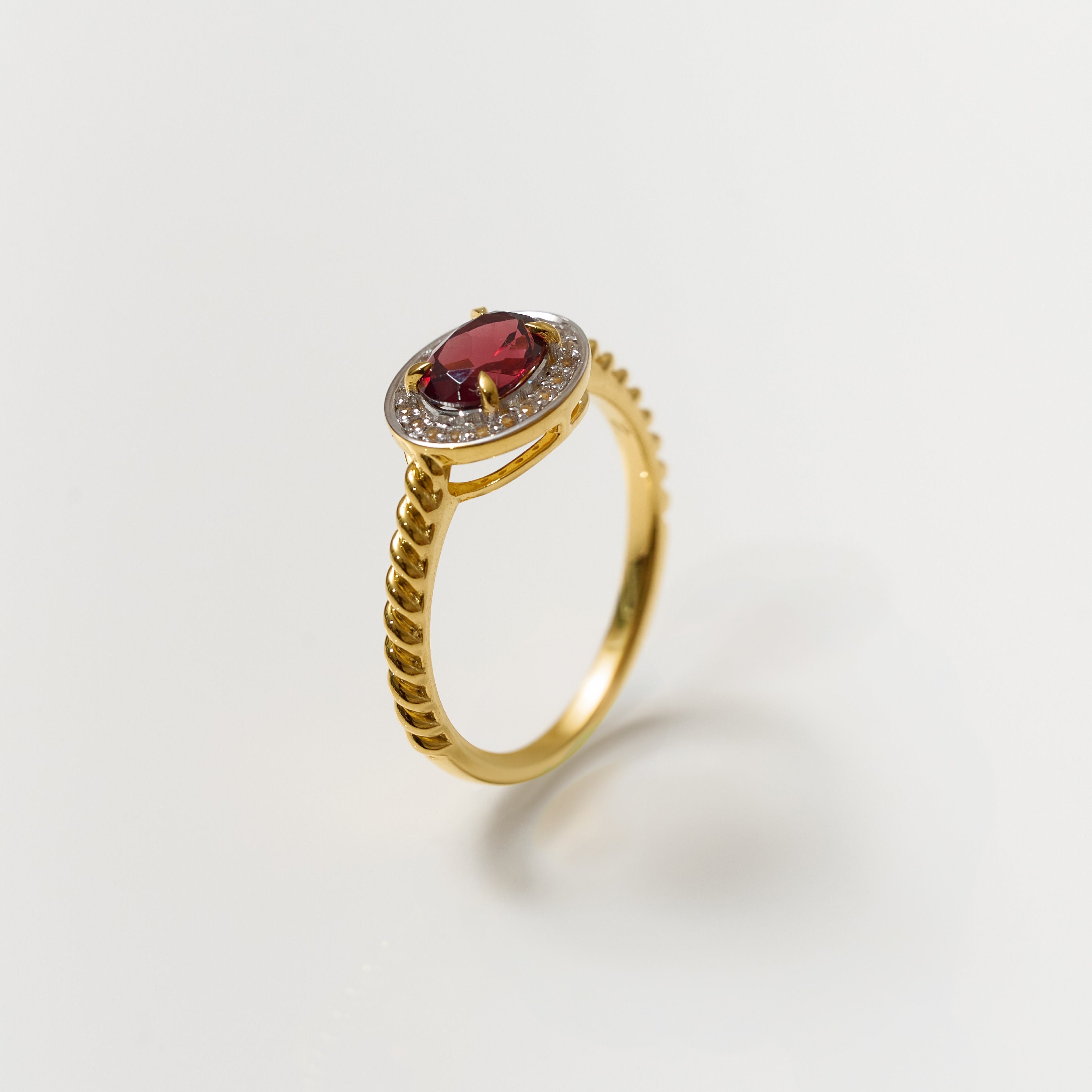 Agira Ring with garnet center and white topaz halo on gold twisted band