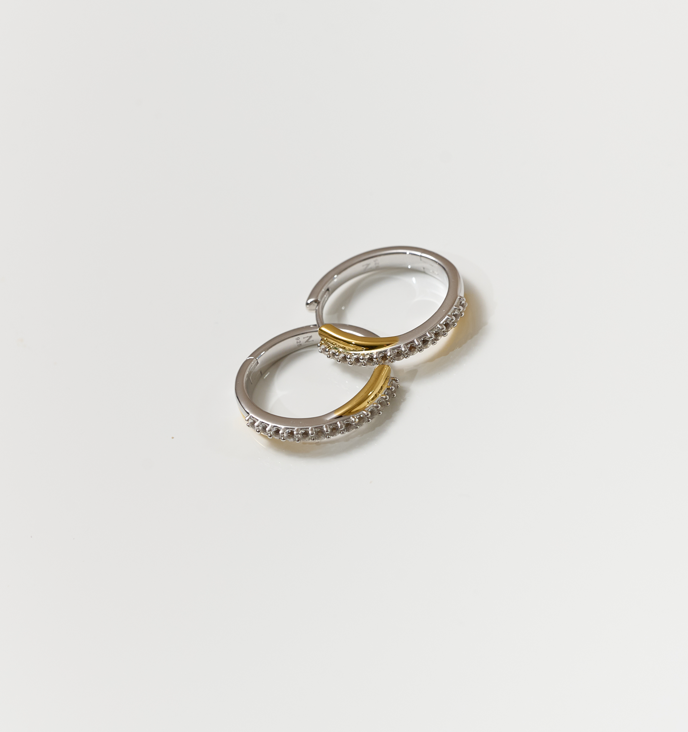 Silver and gold Mishri Hoops earrings with white topaz detailing on a white background