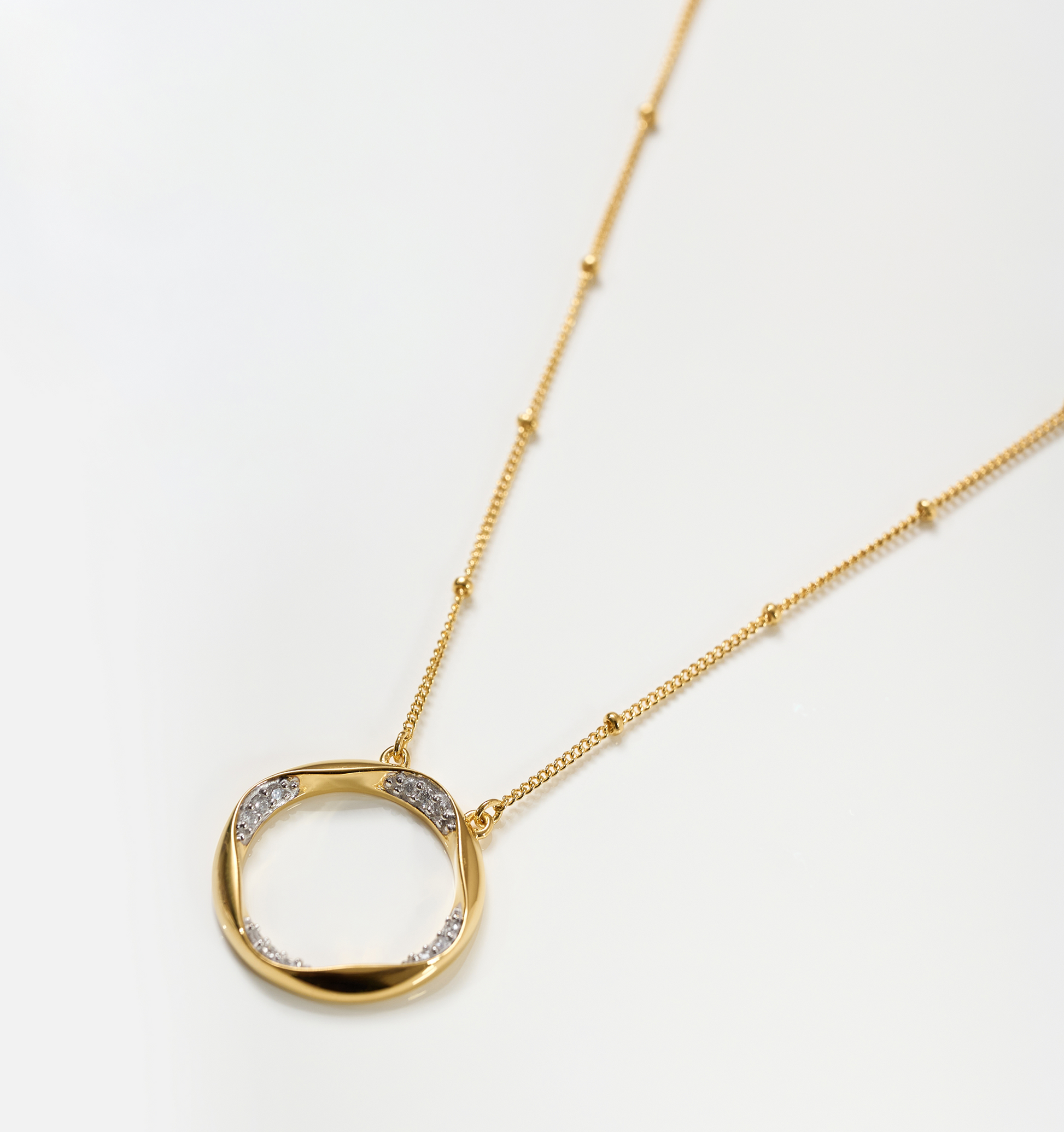 Taral Necklace gold chain with circular pendant featuring white topaz accents