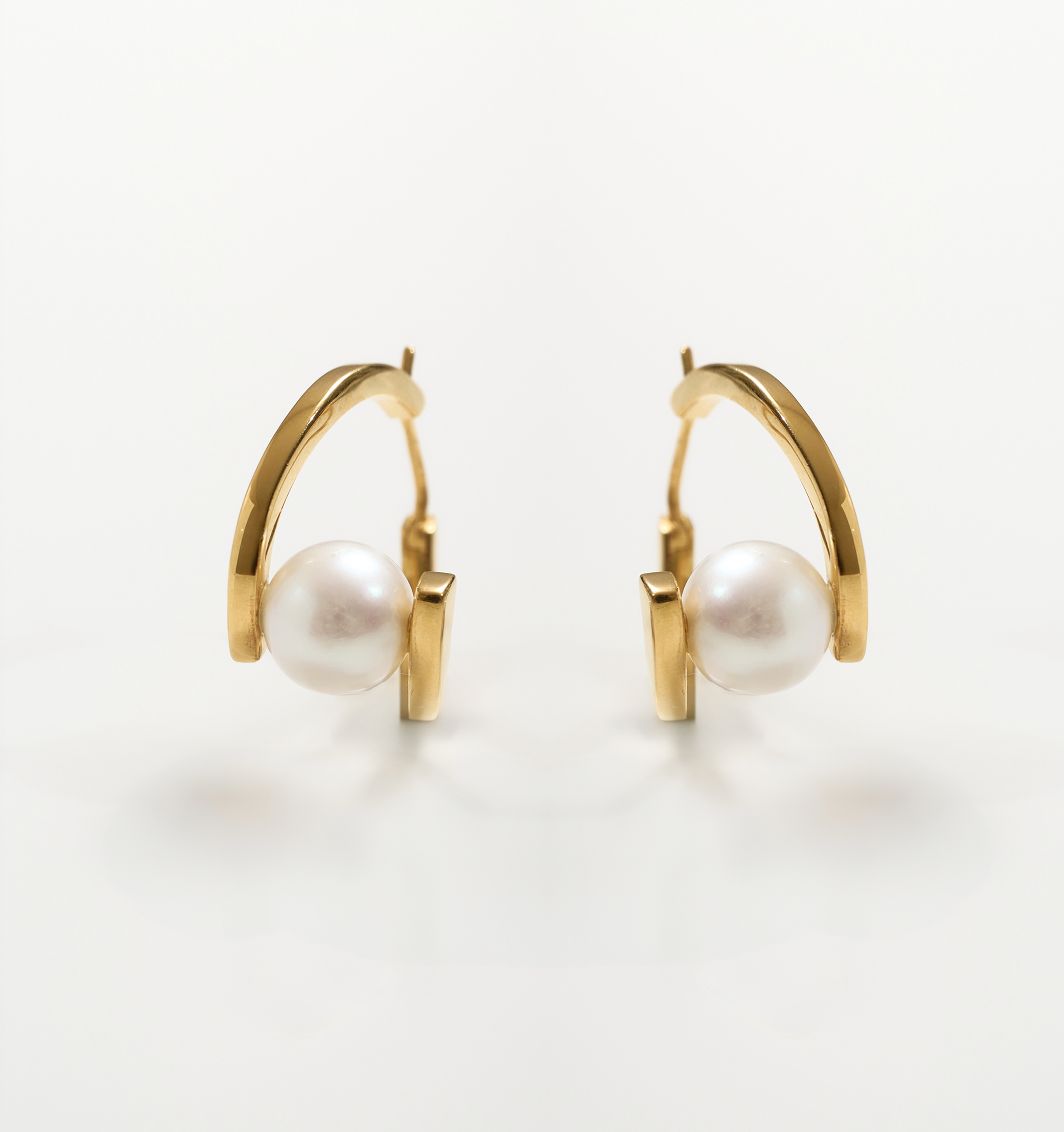 Gold Sharvani Earrings with a pearl accent and horned curve design on white background