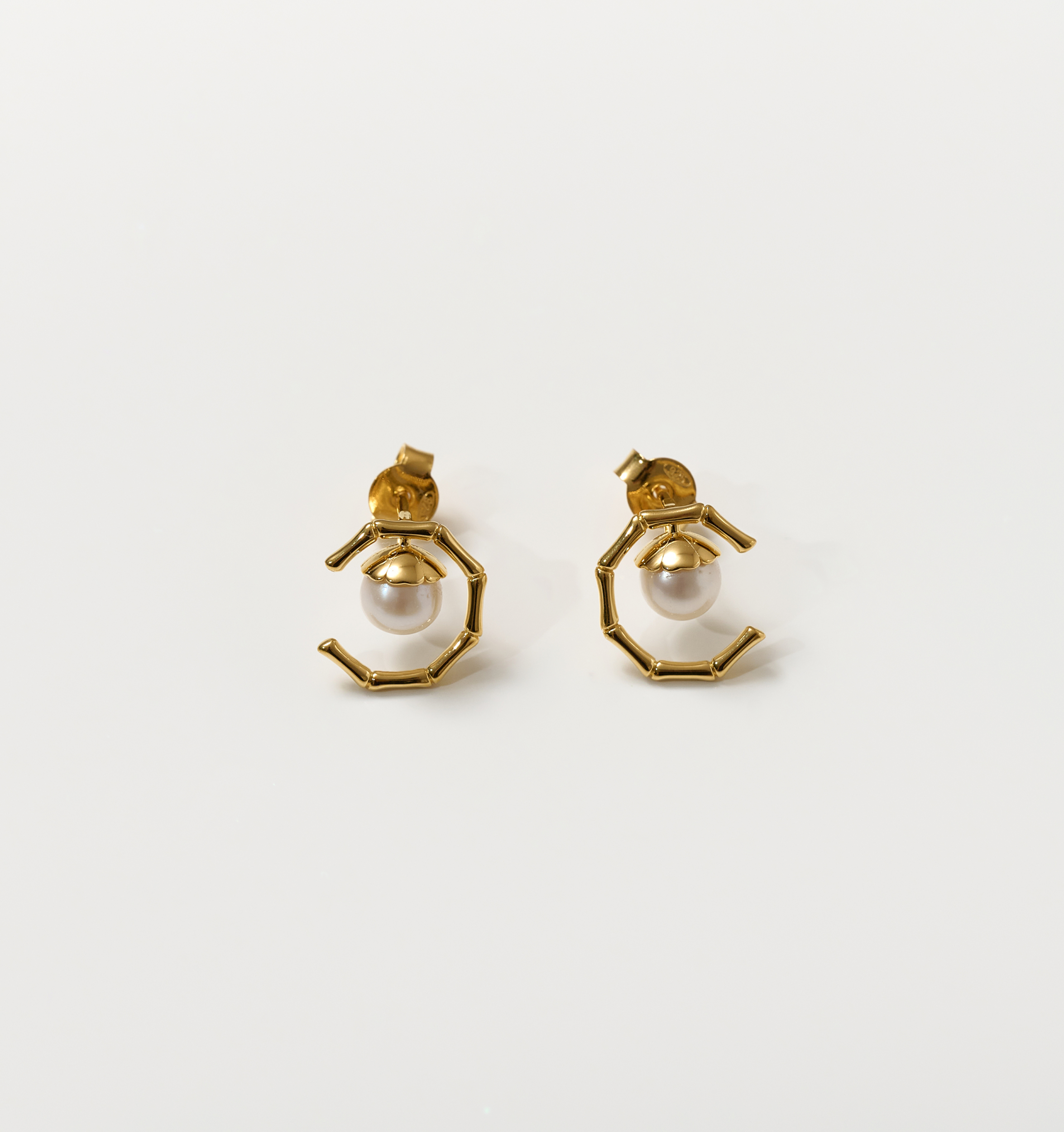Kavach Earrings featuring gold bamboo-like segmented design with a single pearl centerpiece symbolizing resilient elegance and grace.