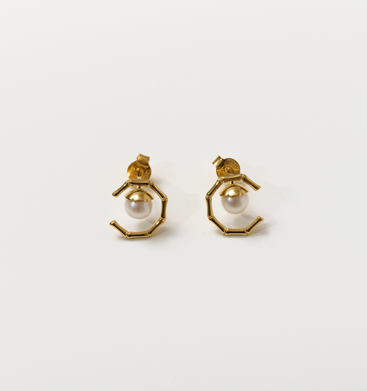 Kavach Earrings featuring gold bamboo-like segmented design with a single pearl centerpiece symbolizing resilient elegance and grace.