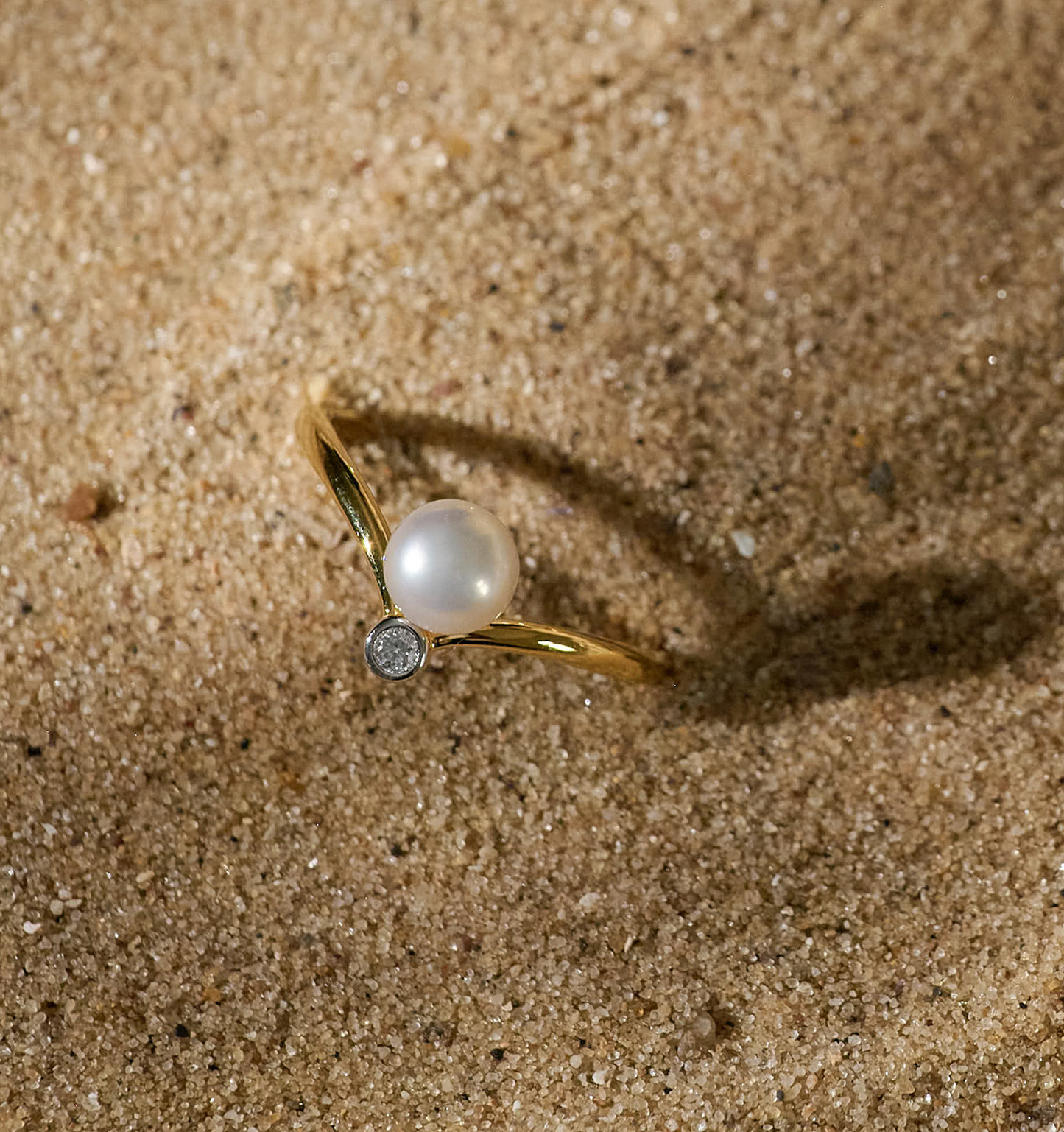 Sirna Ring gold band with pearl and star detail on sandy background